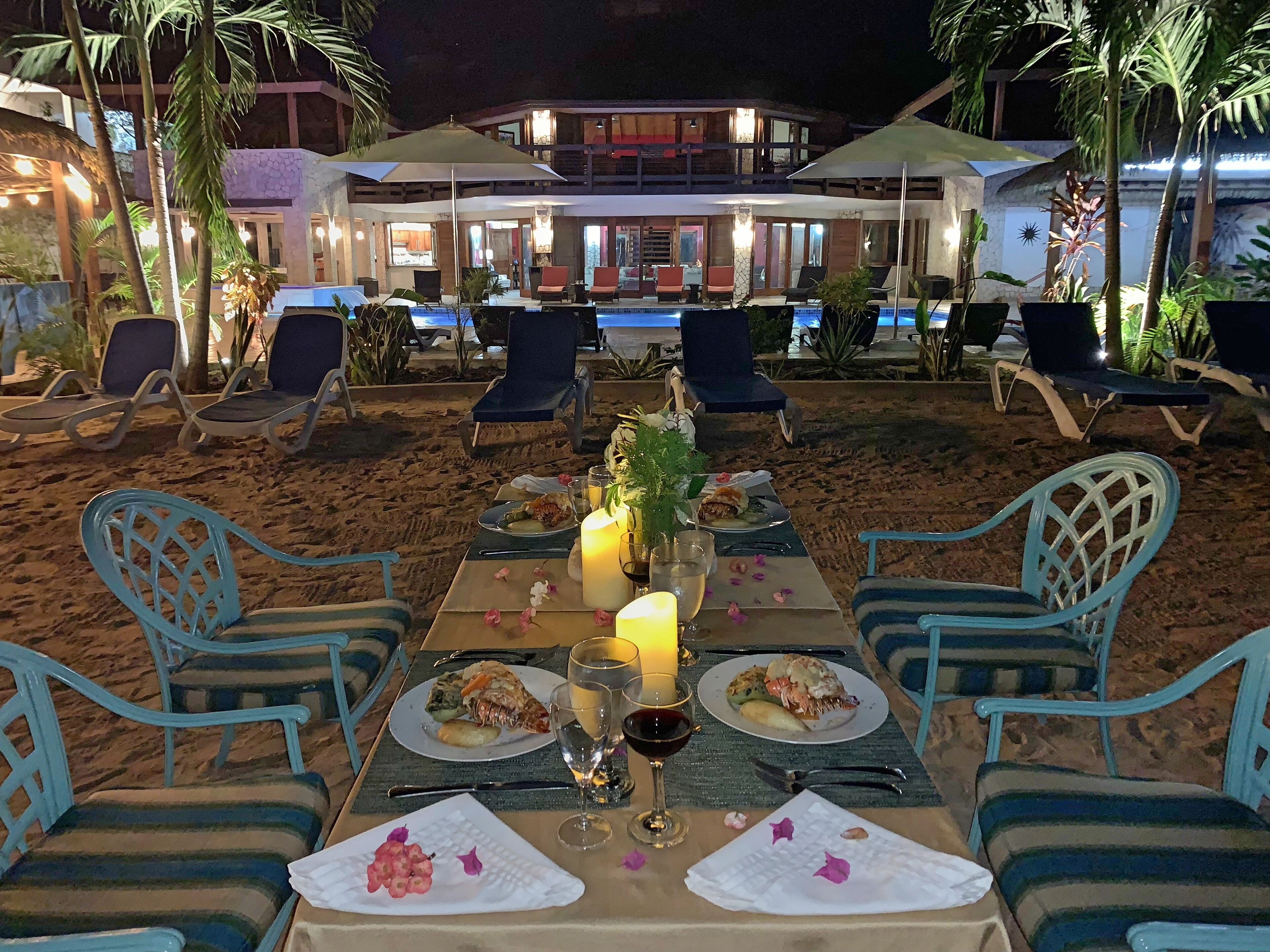 A dining table on the sand at night.