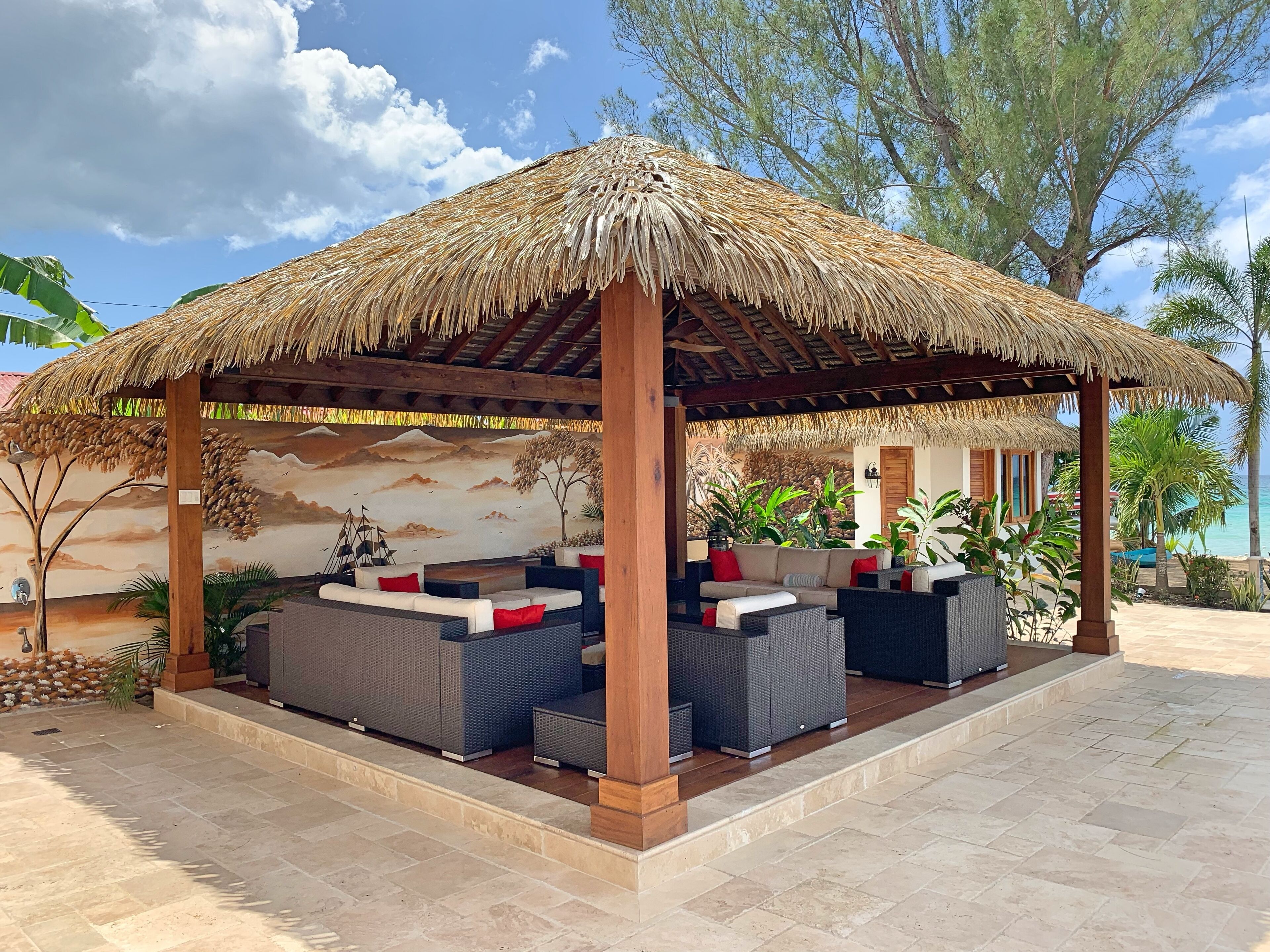 A thatched gazebo with sofas.