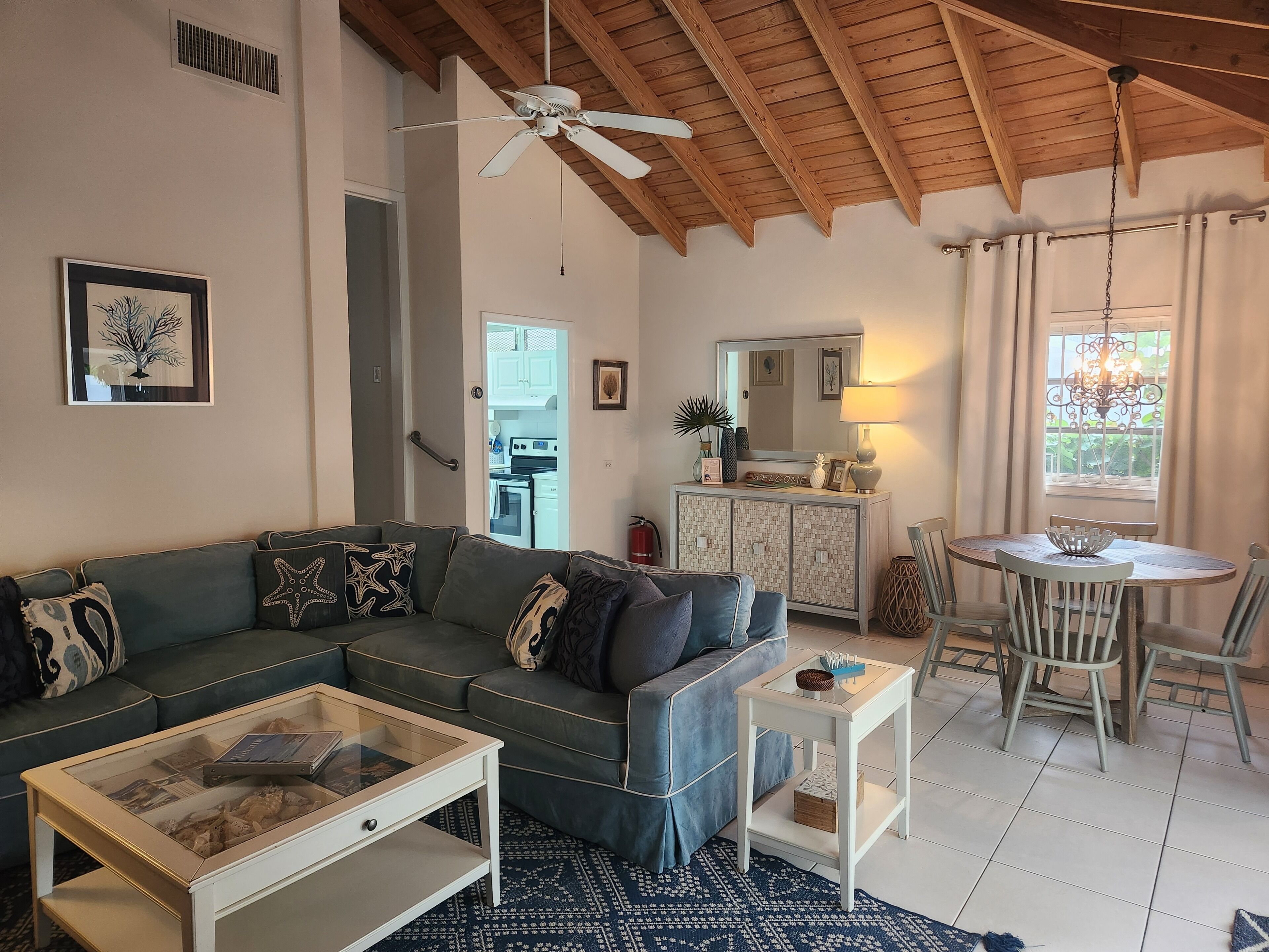 A living room with a blue corner sofa and a wood beam ceiling.