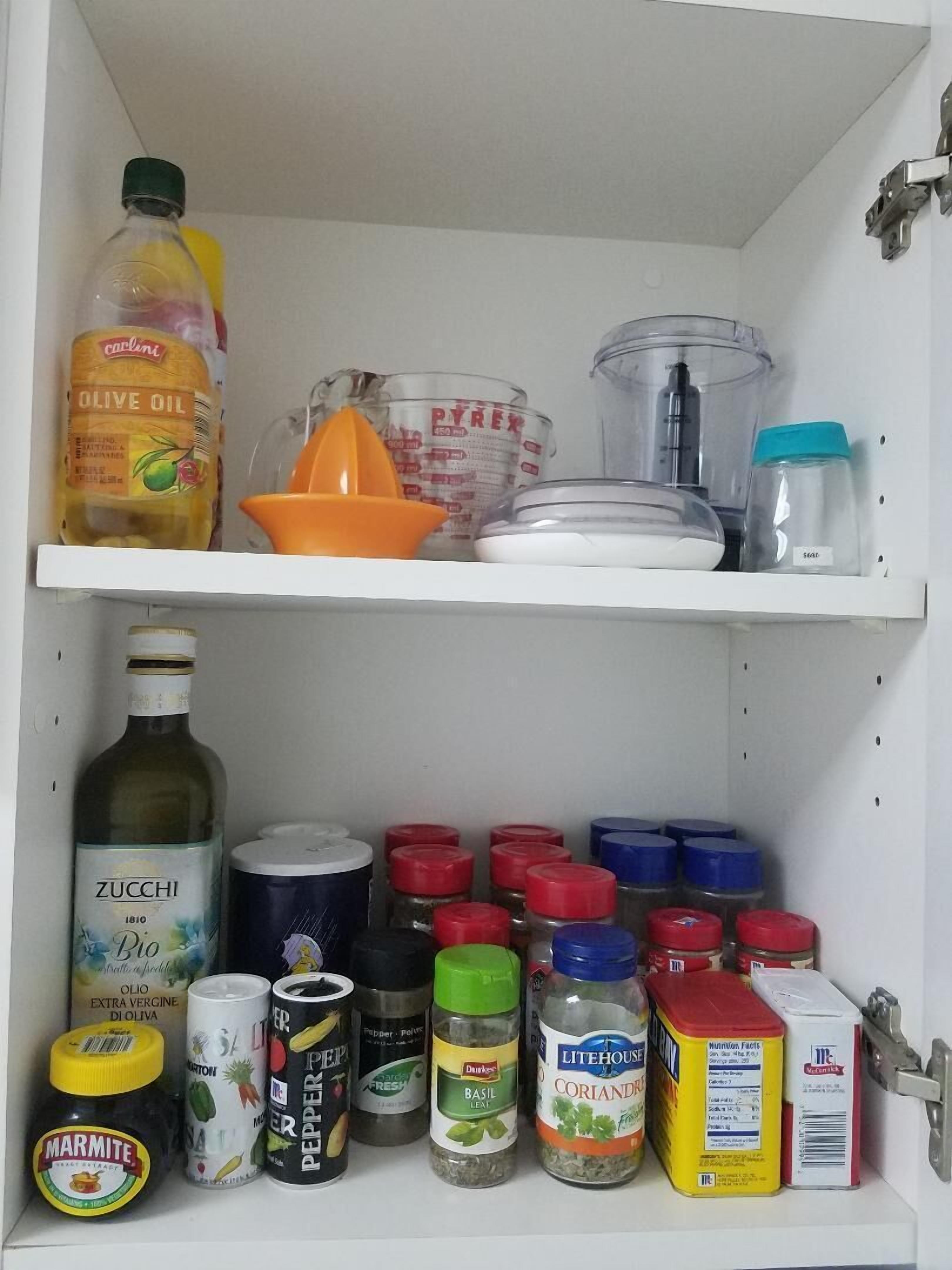 A kitchen cabinet with oils, spices, and small appliances.