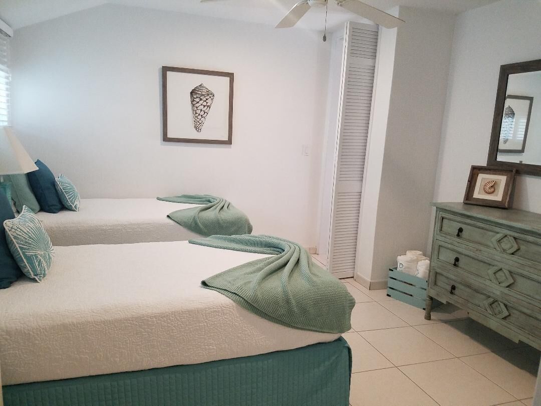 A bedroom with two single beds and a mirror above a dresser.