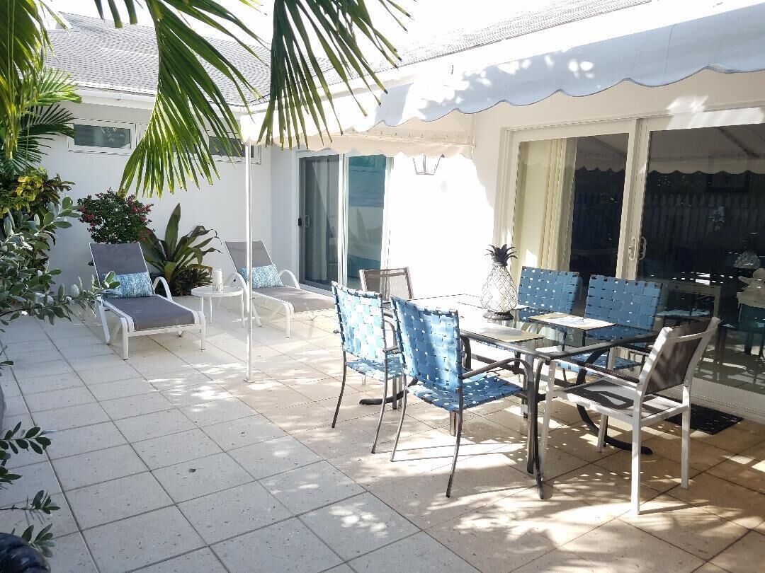 The patio with sun loungers and a dining table in daylight.