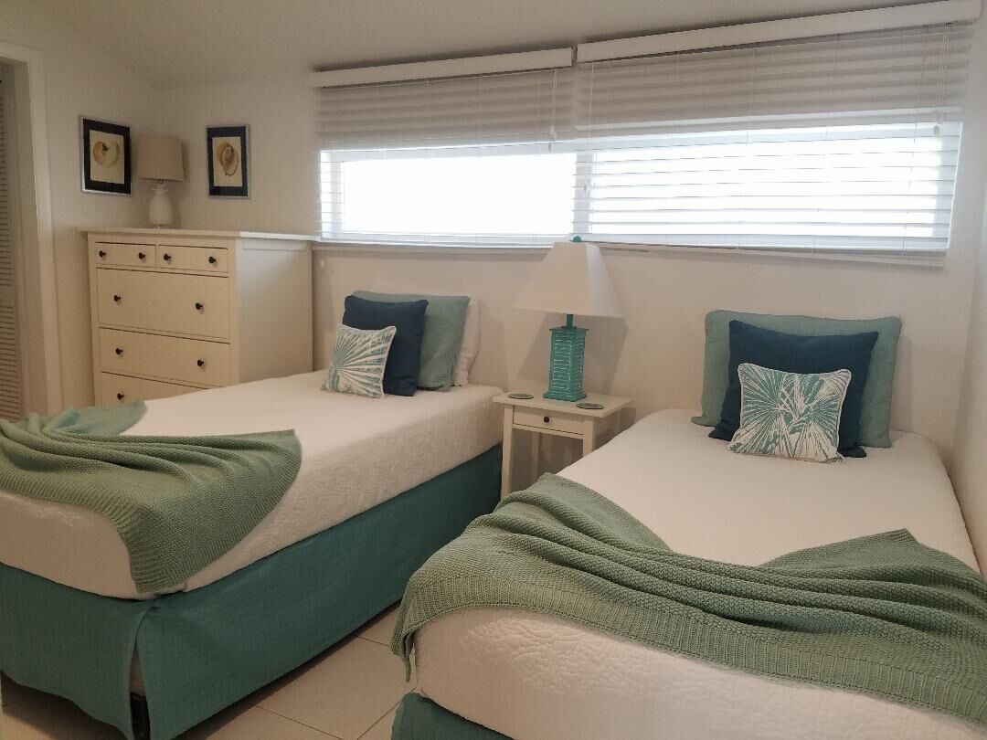 A bedroom with two single beds and a table lamp between them.