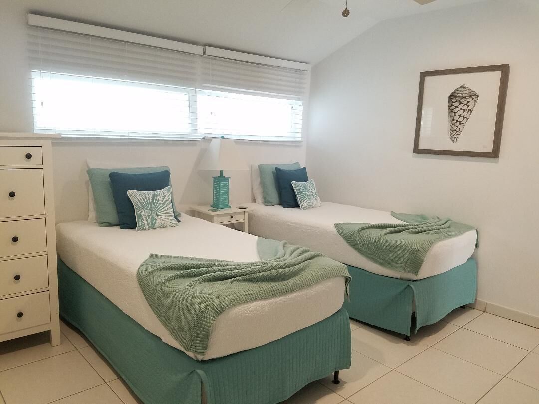 A bedroom with two single beds and a shell picture.