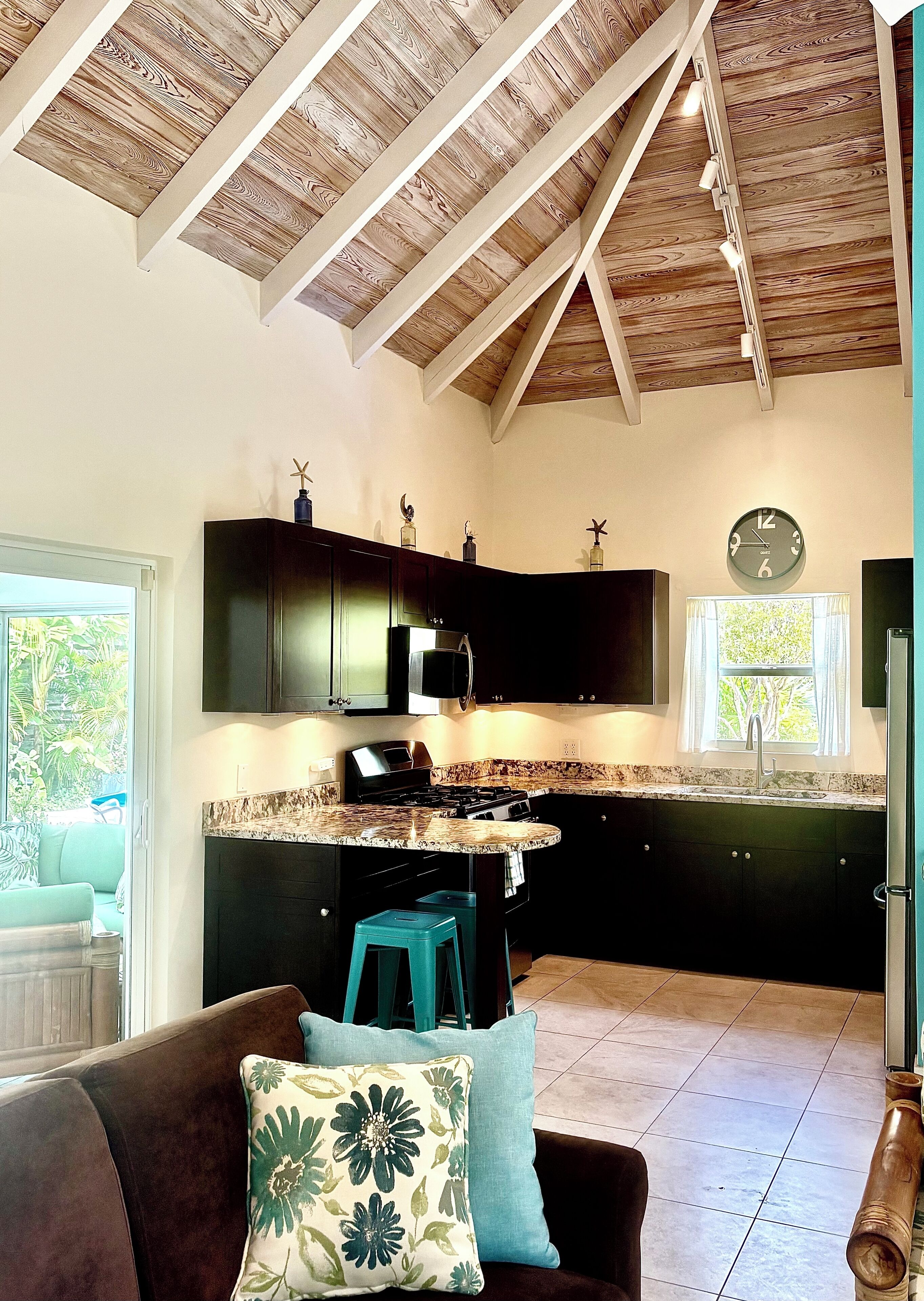 The kitchen has dark cabinets under a vaulted wood ceiling.
