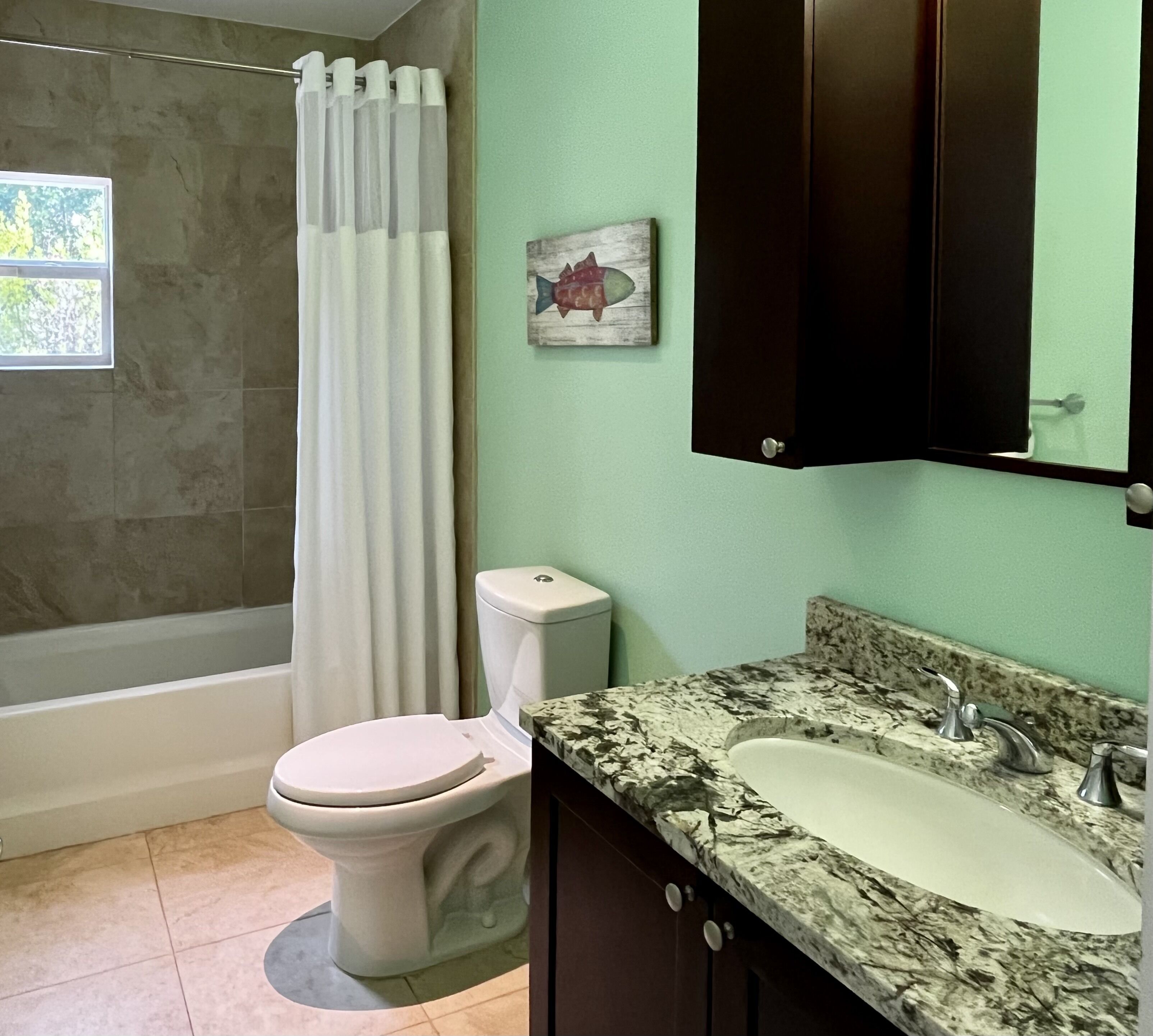 The bathroom has a bathtub, a toilet, and a granite counter.