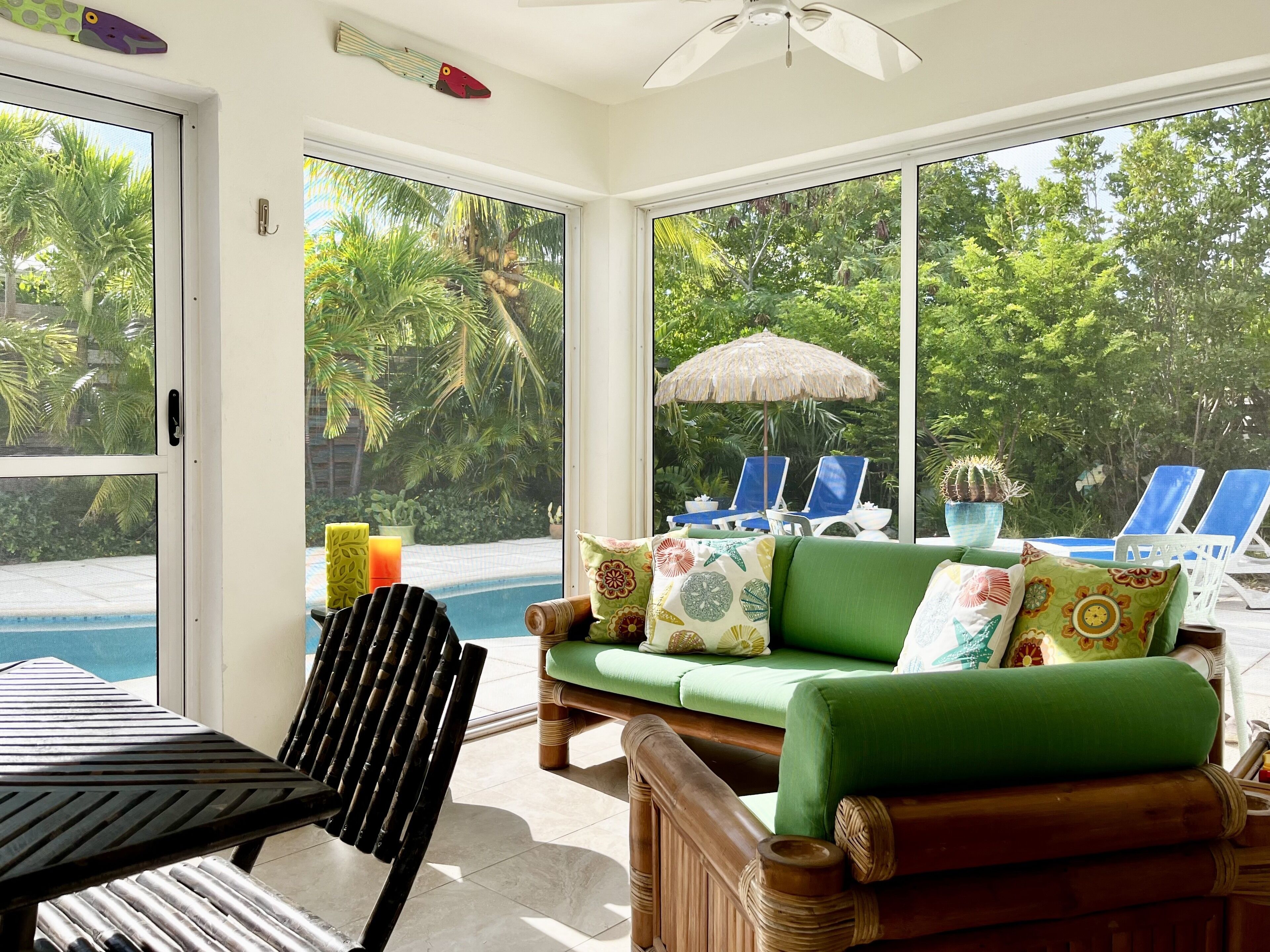 The screened room has a green sofa and a view of the pool.