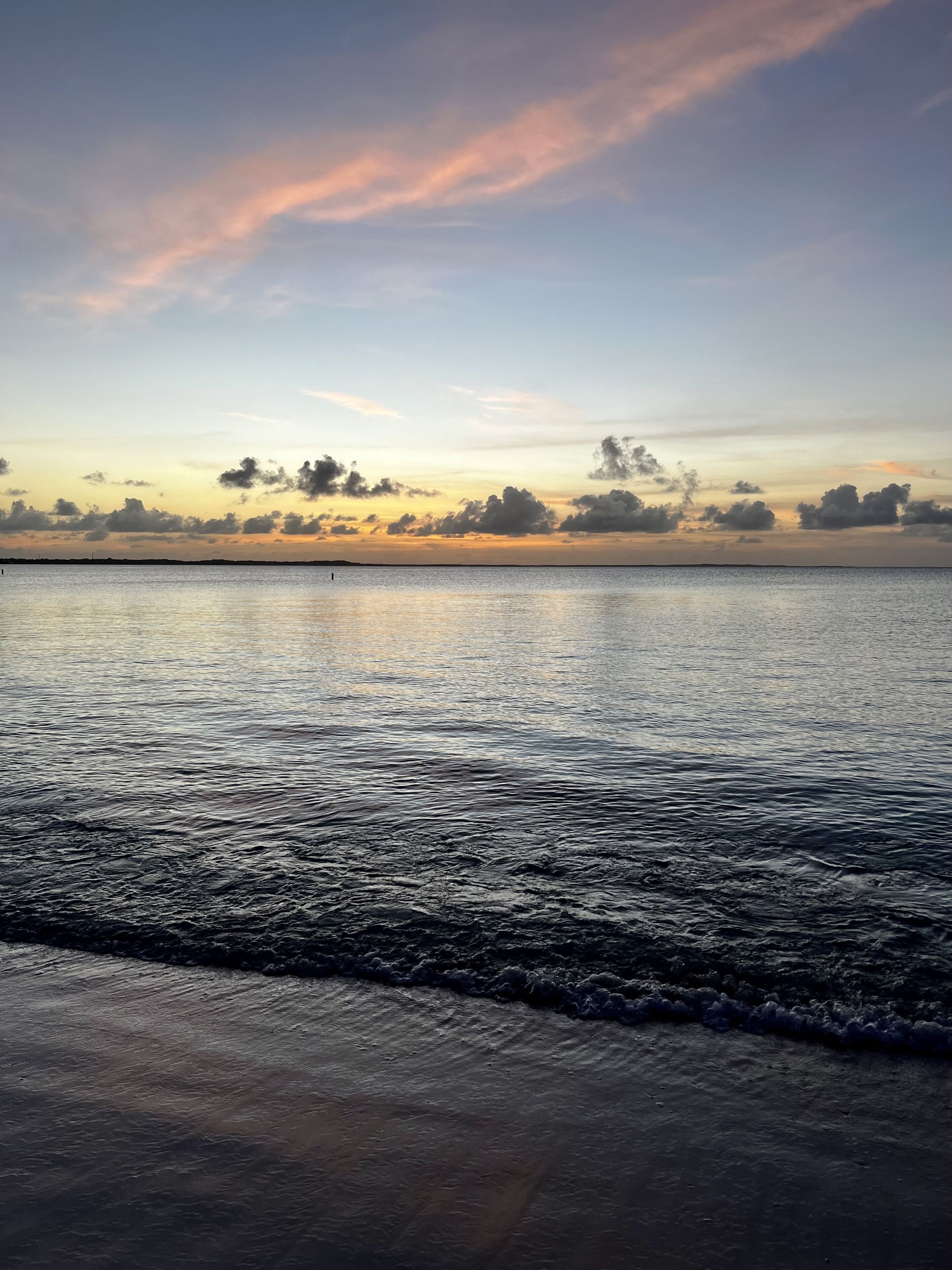 The sun sets over the calm sea.