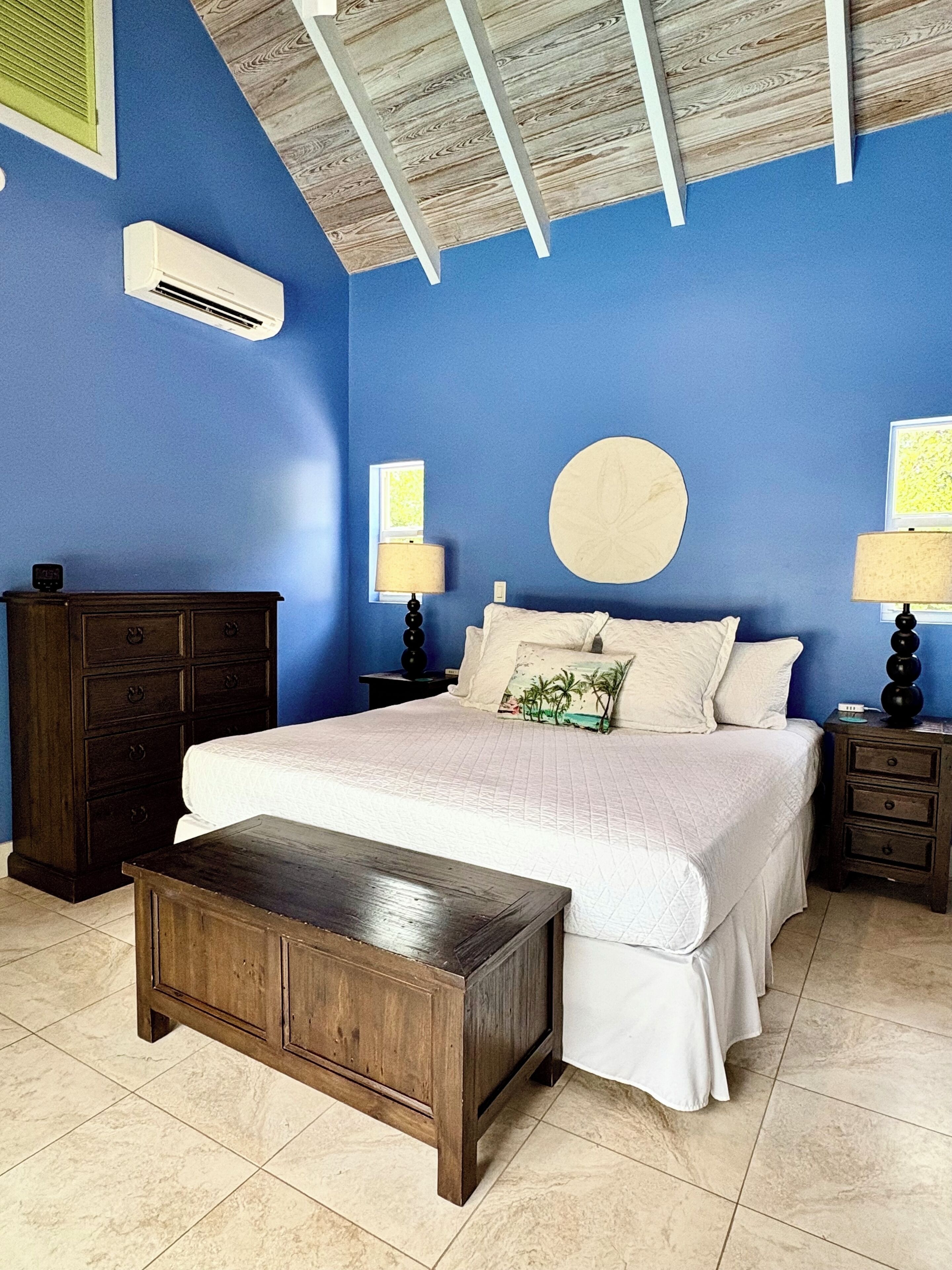 The bedroom has blue walls, a white bed, and wood furniture.