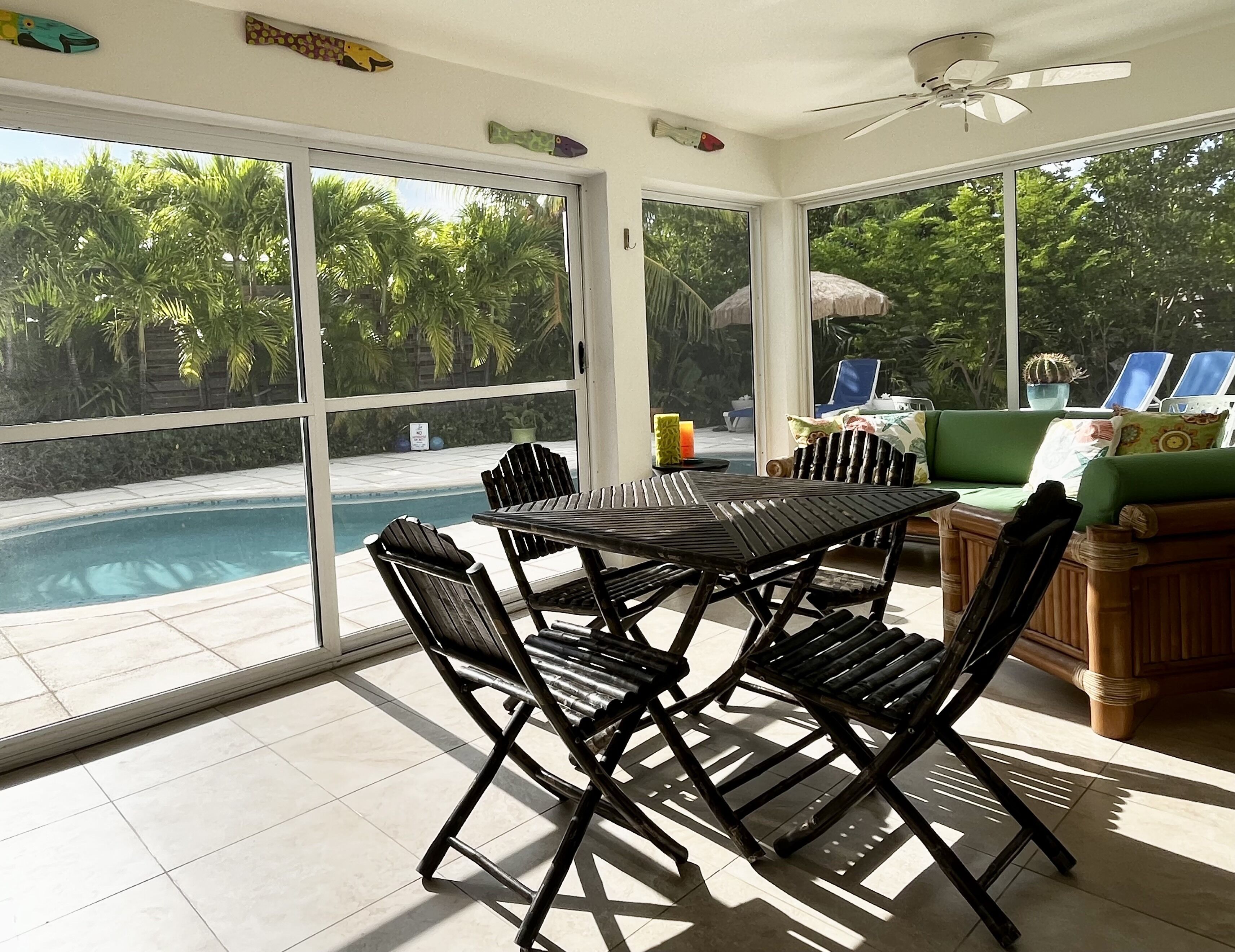 The screened room has a bamboo dining table with four chairs.