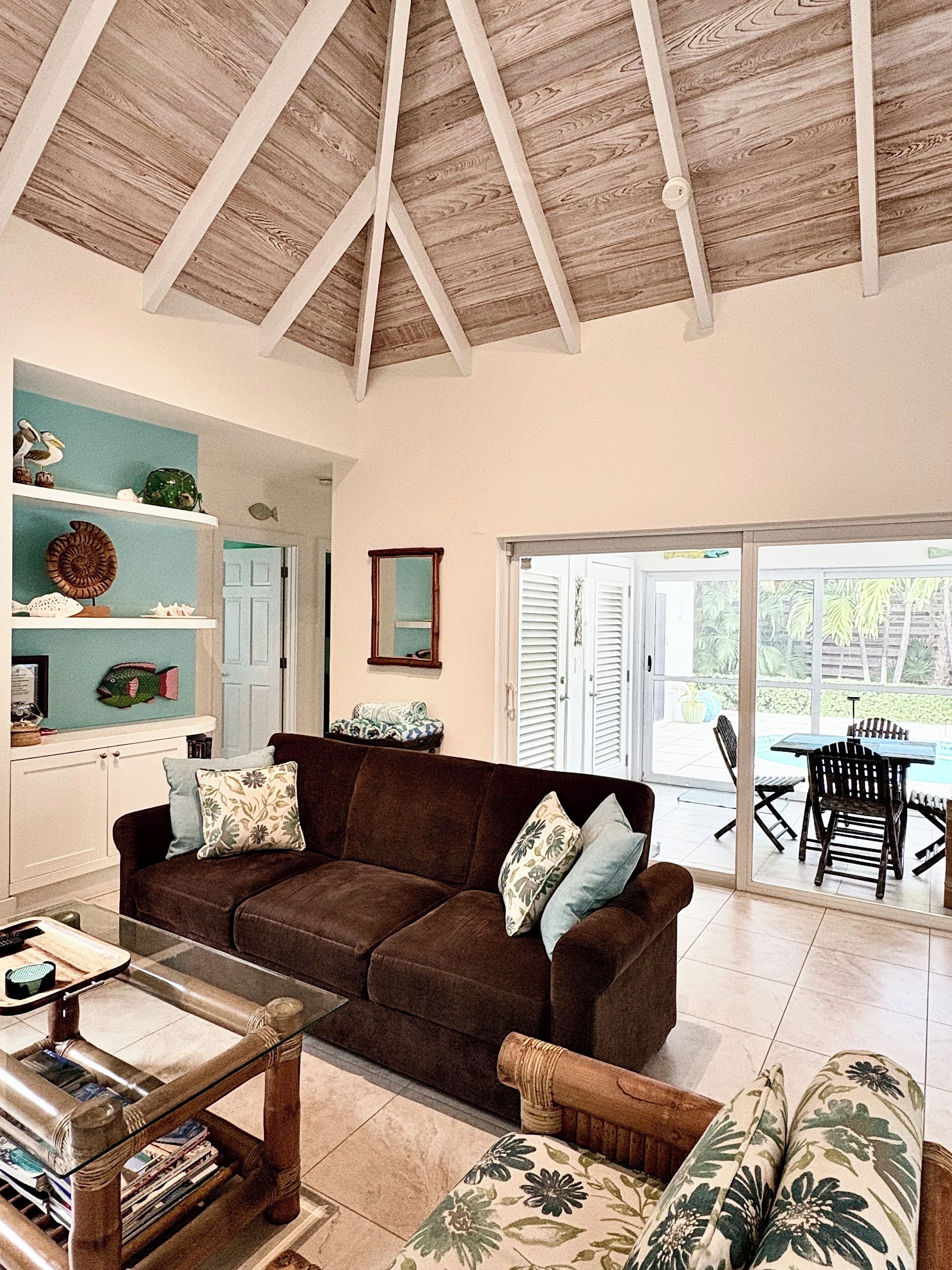 The living room has a brown sofa under a vaulted wood ceiling.