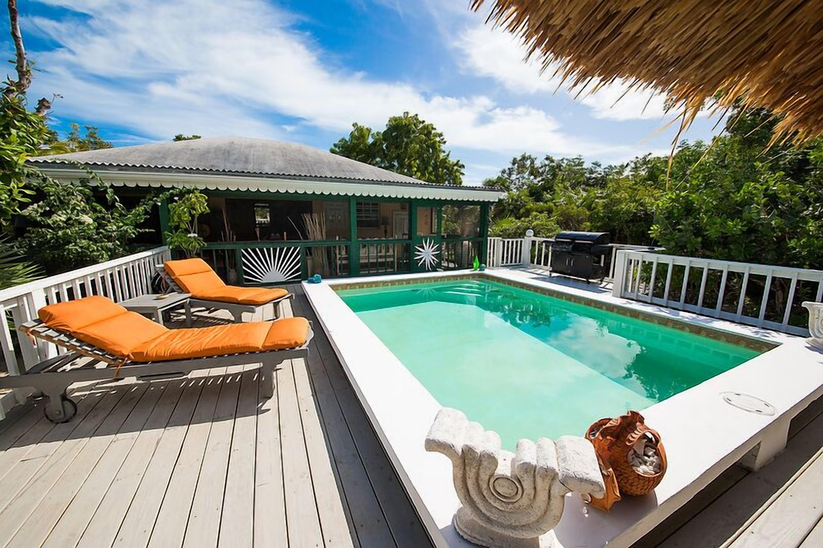 The pool, two orange loungers, and the villa.