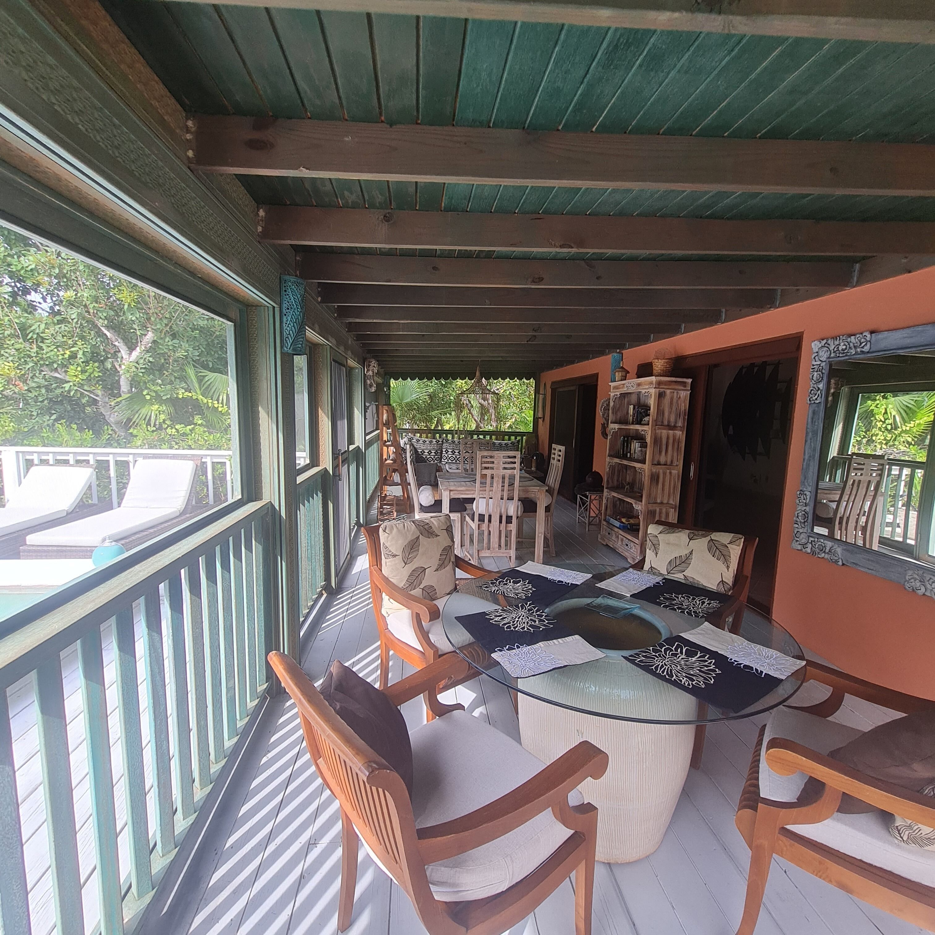 A round glass table and chairs on the porch.