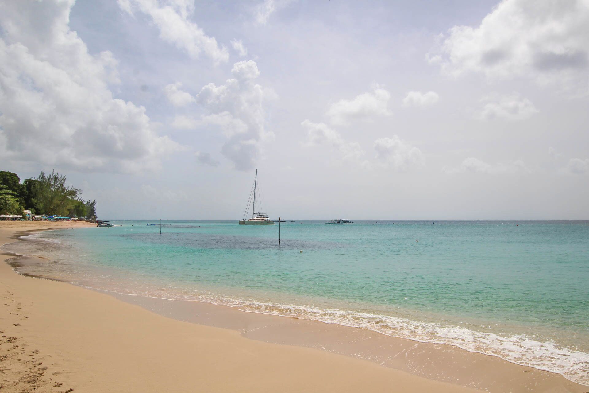 A sandy beach near the villa, with boats offshore.