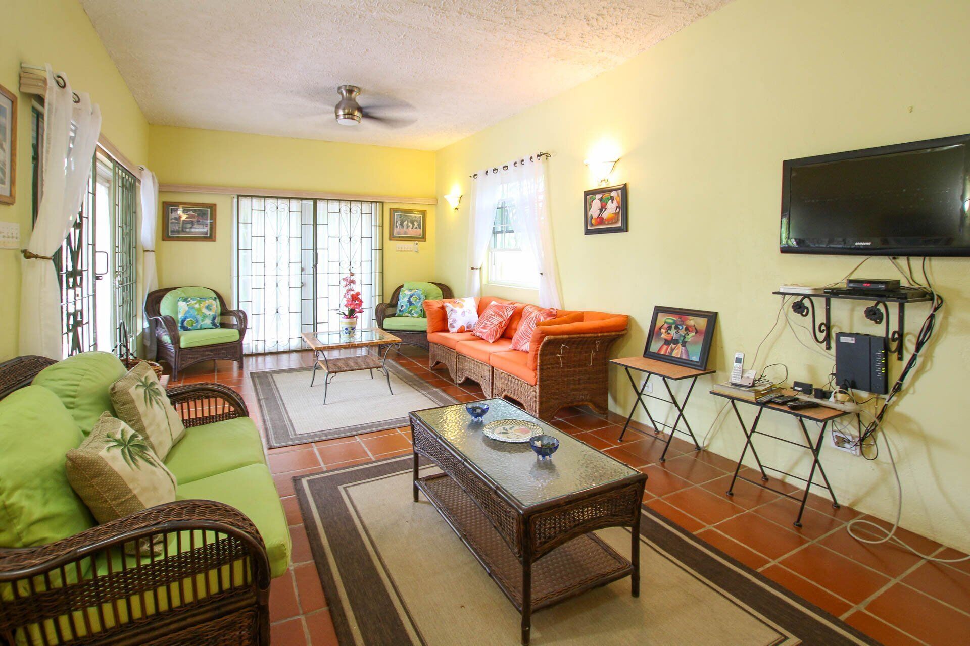 The living room with wicker seats and a wall television.