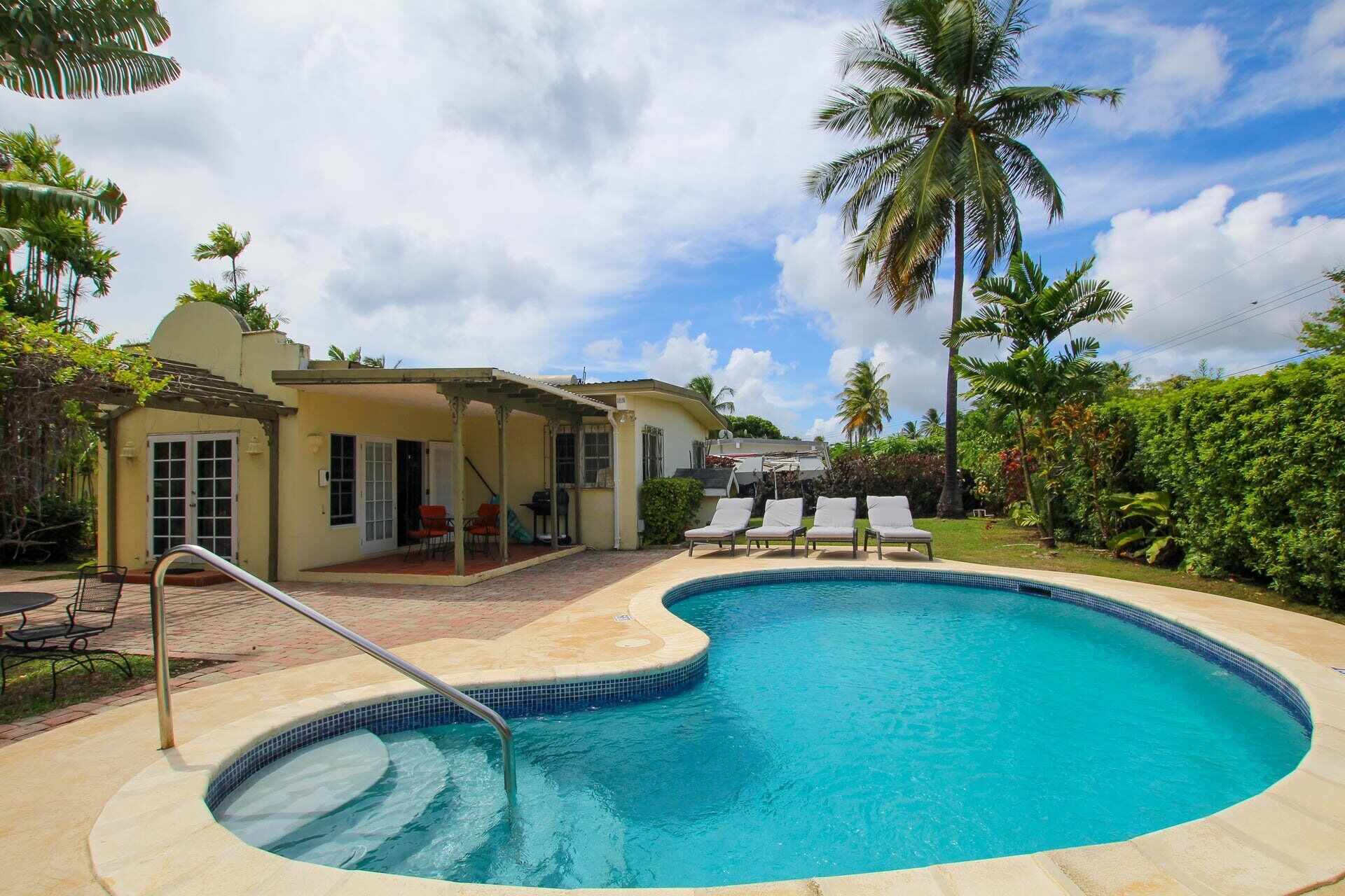 The covered patio with a table, with the pool beyond.