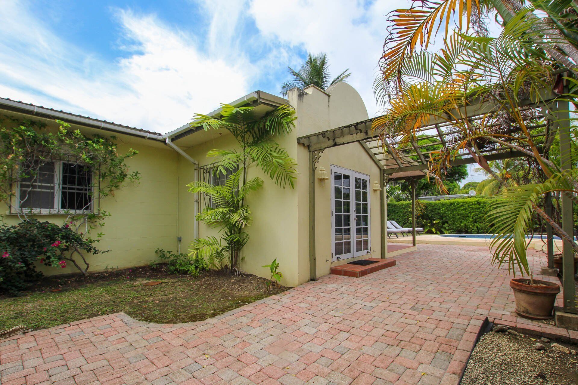 The villa exterior with a paved courtyard and a pergola.