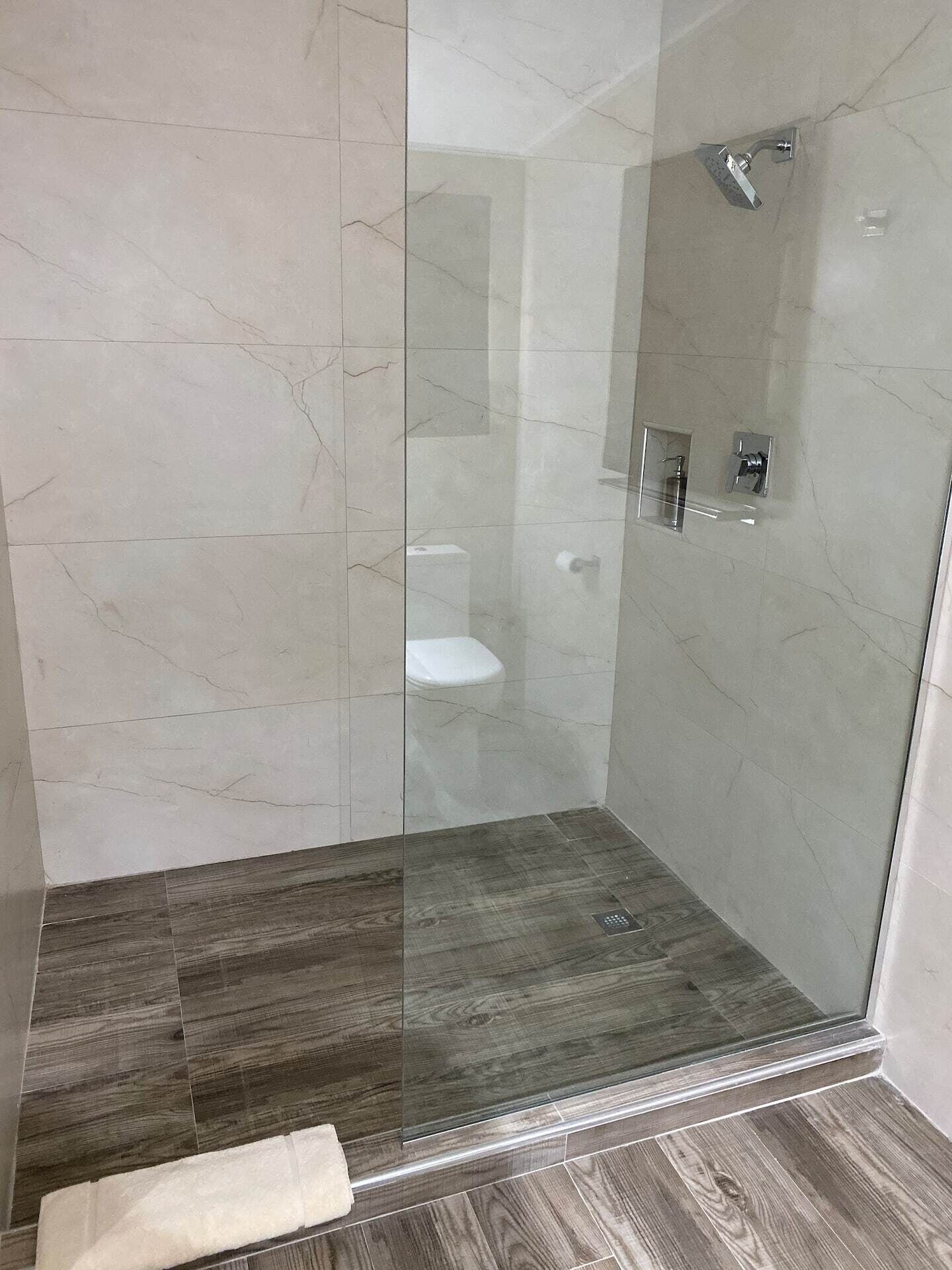 A bathroom with a walk-in shower behind a glass panel.