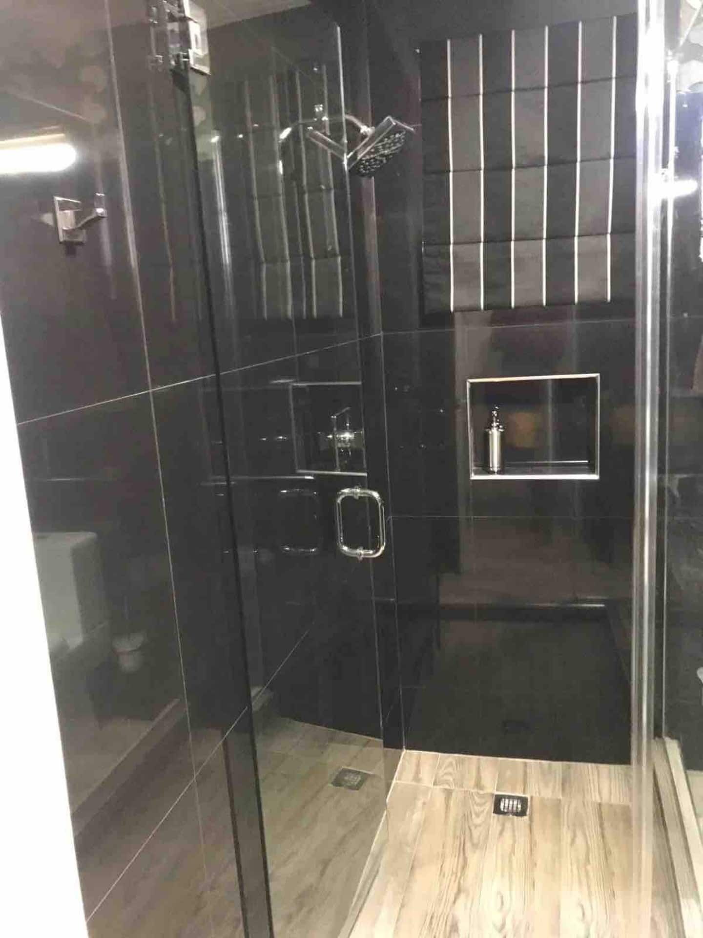 A bathroom with a dark-tile shower and a glass door.
