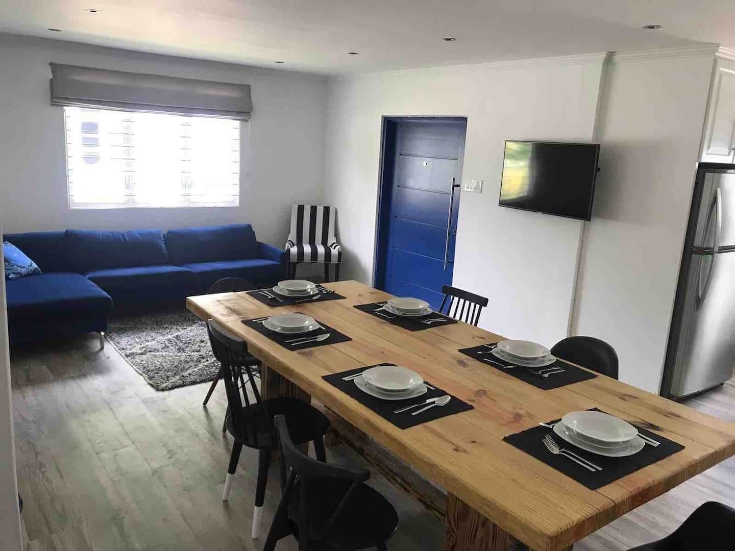 A dining table with six place settings next to the living area.