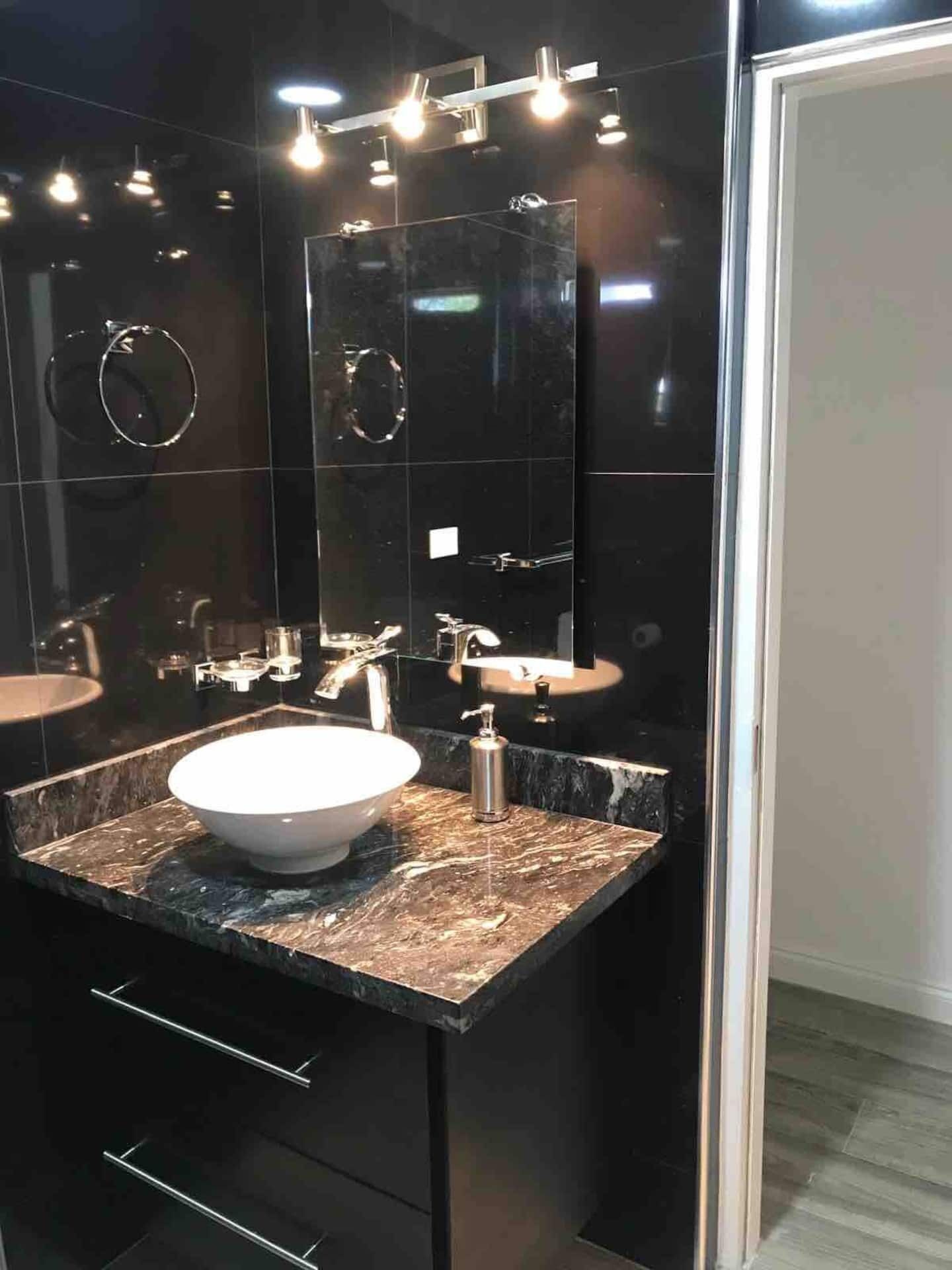 A bathroom vanity with a bowl sink and a stone counter.