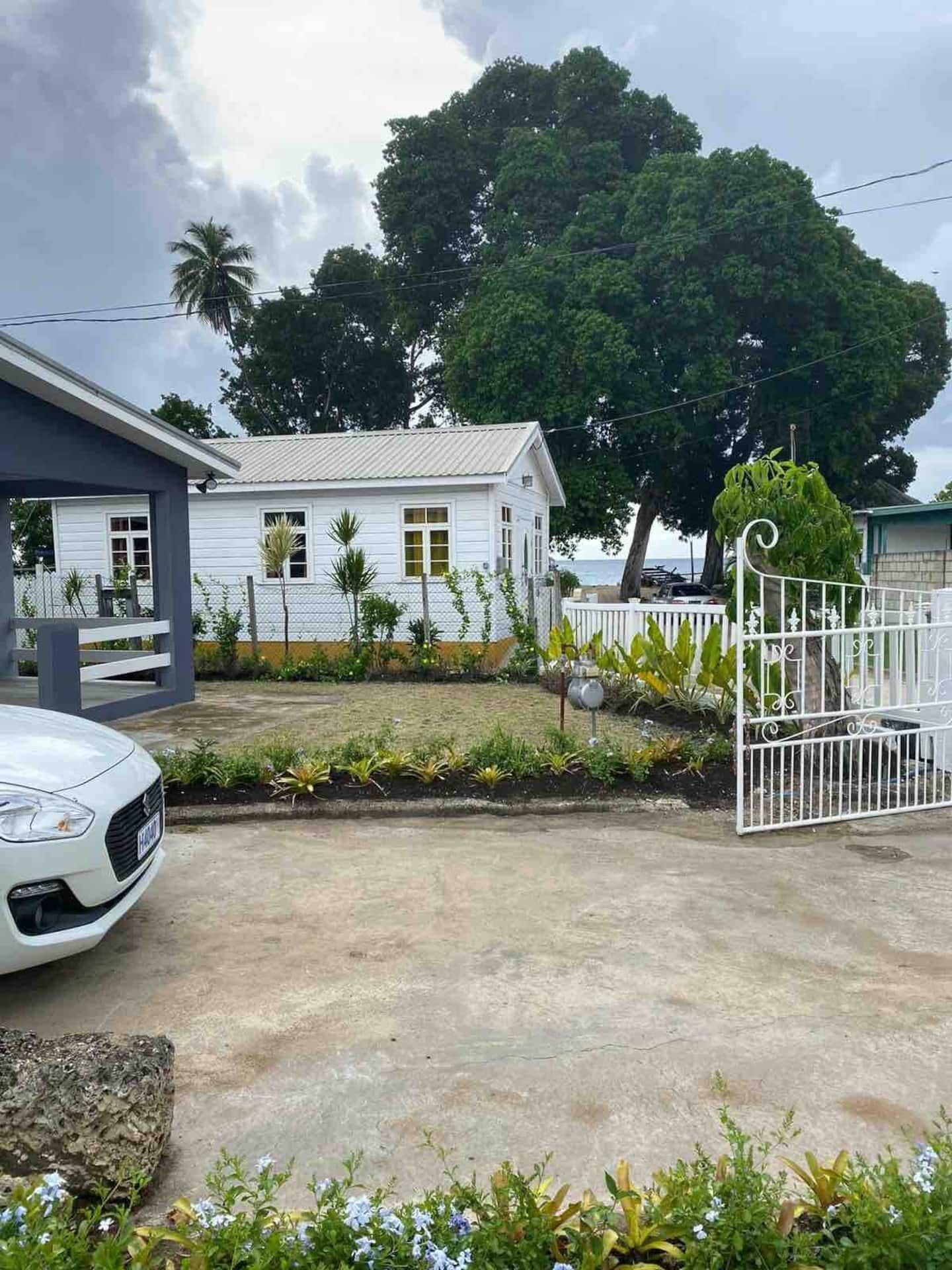 A garden with a white fence and a view to the sea.
