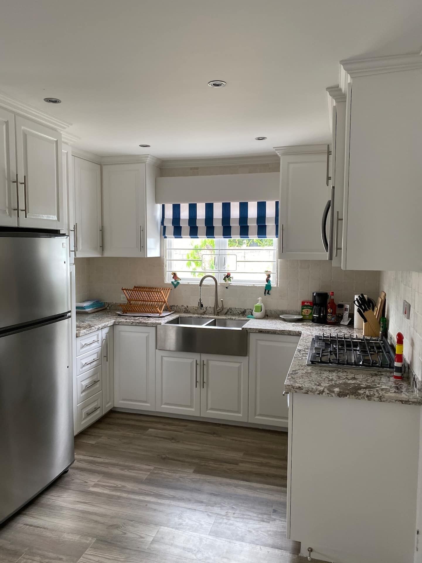 A kitchen with white cabinets, a steel refrigerator, and a gas cooktop.