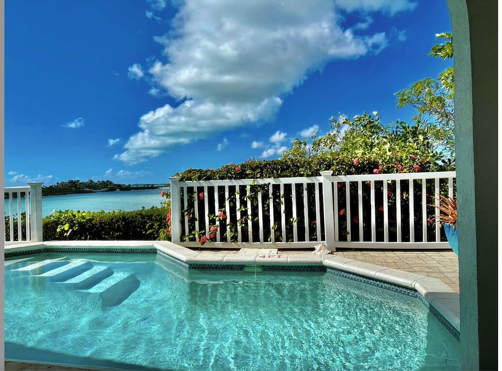 The pool with steps, a white fence, and a view of the water.