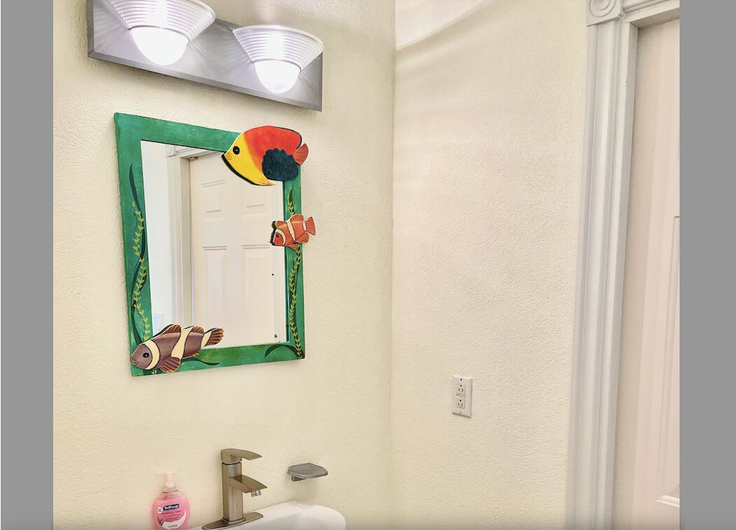A bathroom mirror with a frame that shows painted fish.
