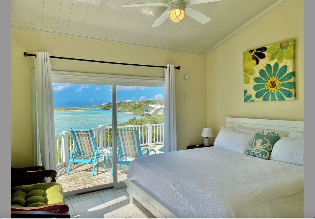 A bedroom with a bed and a glass door with a view of the water.