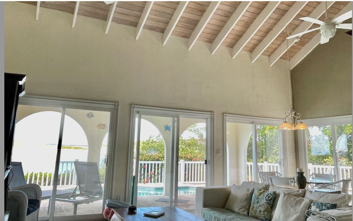A living room with a high wood ceiling and glass doors to the pool terrace.