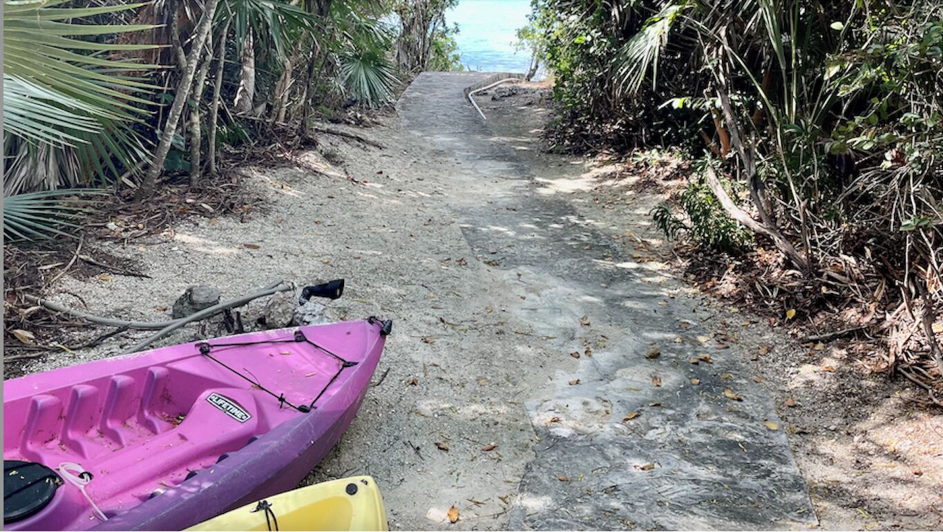 Kayaks next to a path that goes down to the water.