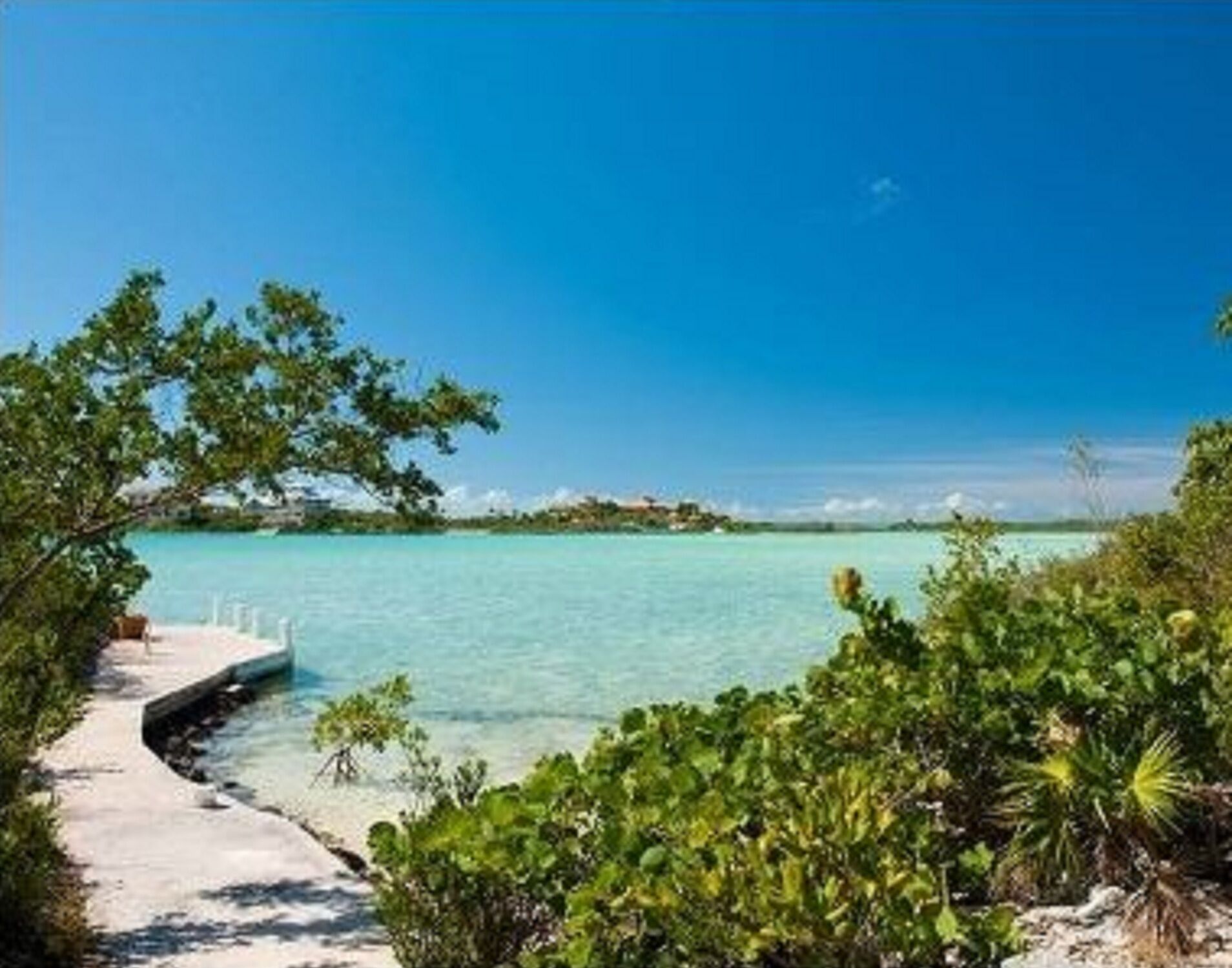 A walkway to a dock on the shore of clear water.