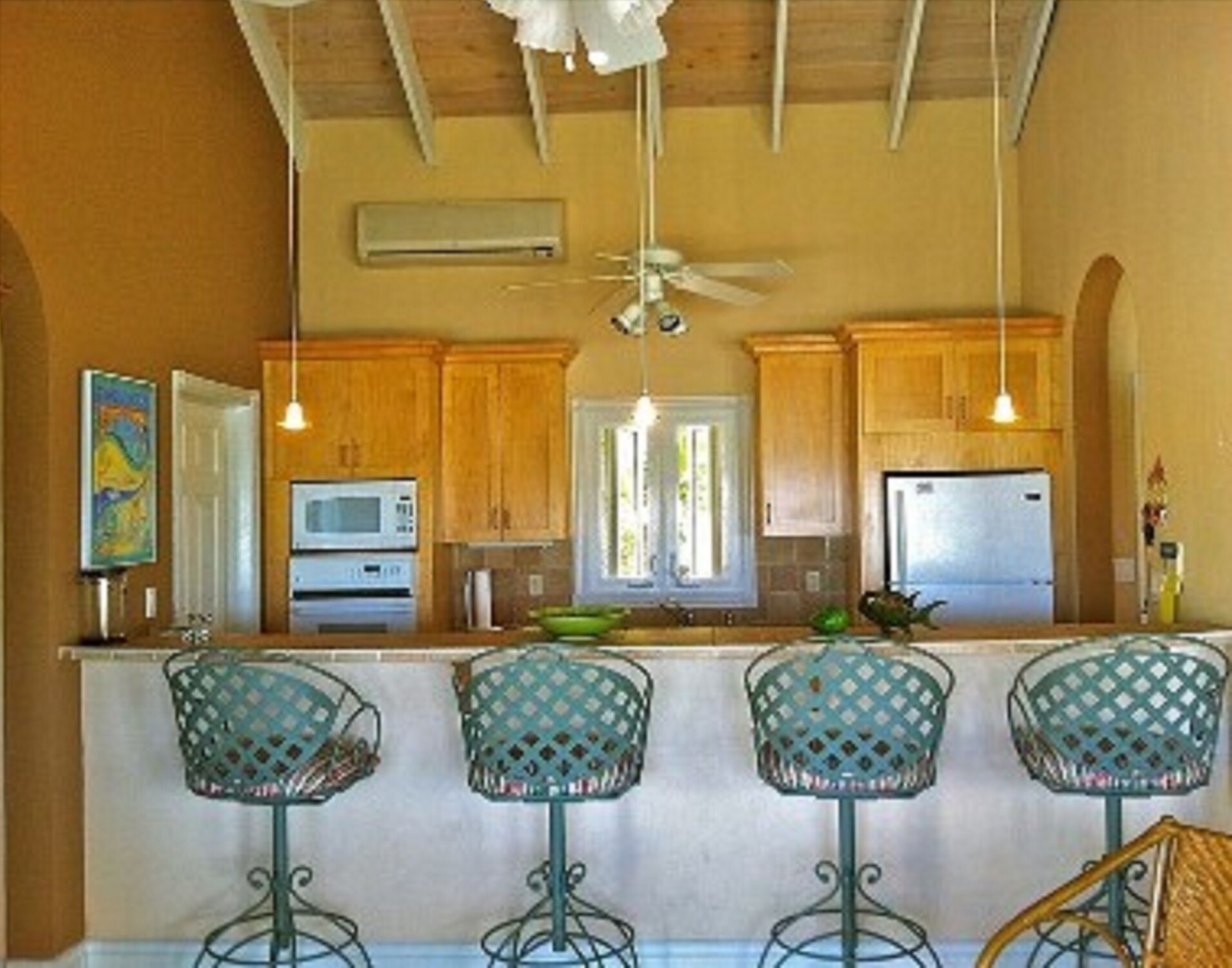A kitchen with wood cabinets and four stools at a counter.