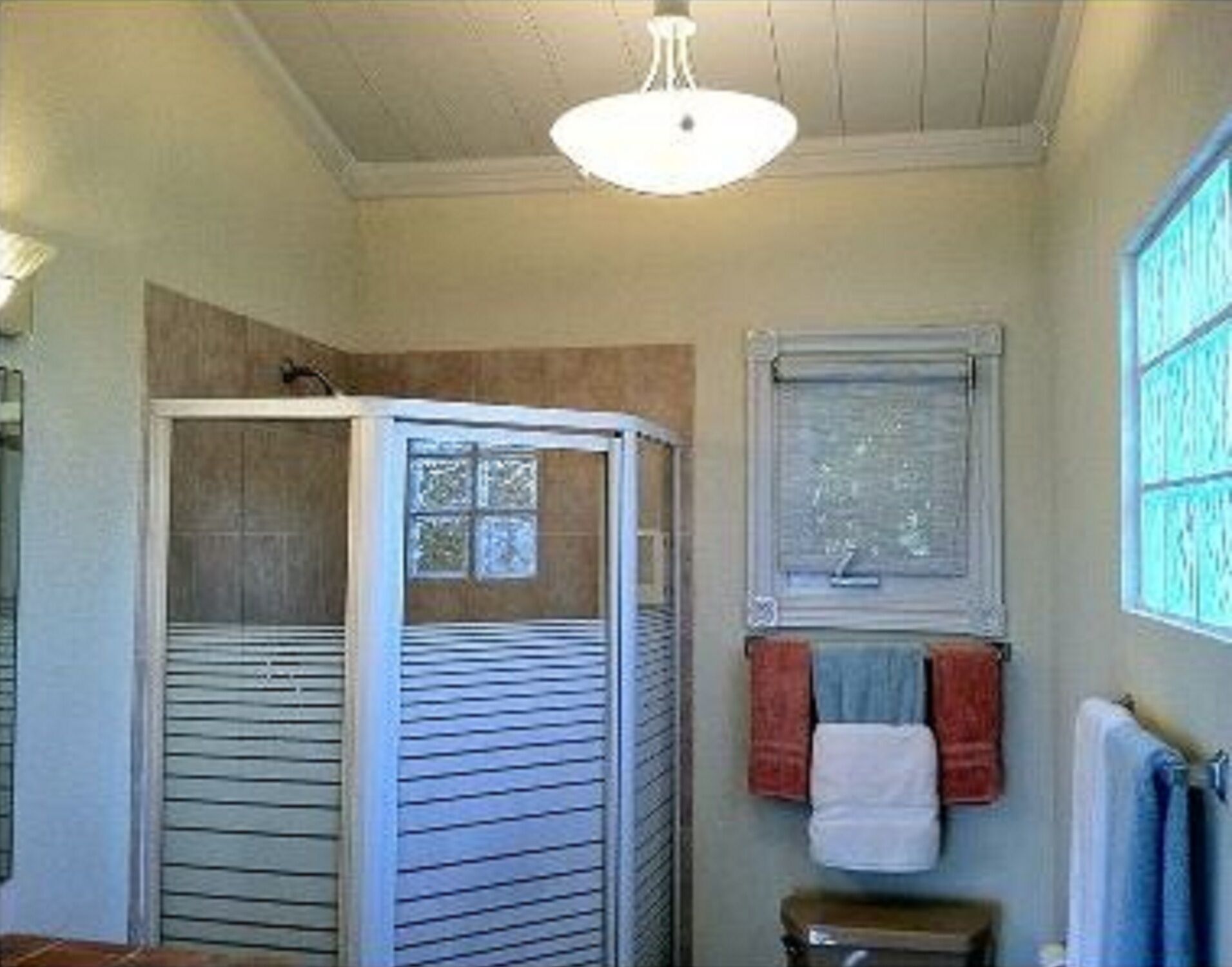 A bathroom with a corner shower and towels.