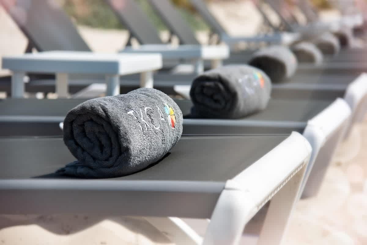 Rolled gray towels lie on a row of sun loungers.