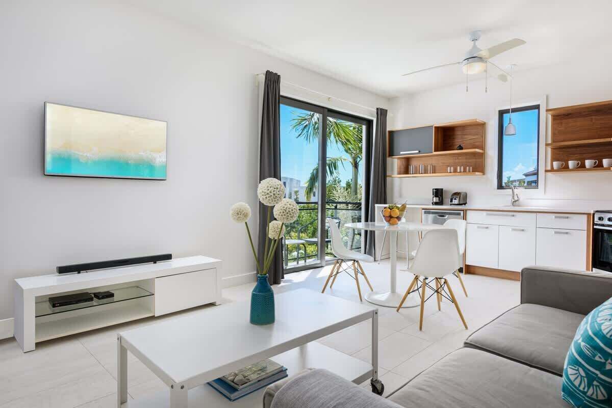 The living area has a sofa, a kitchen, and a small dining table.