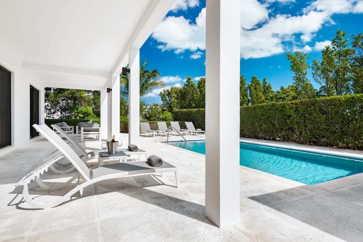 Two sun loungers stand on the covered terrace next to the pool.