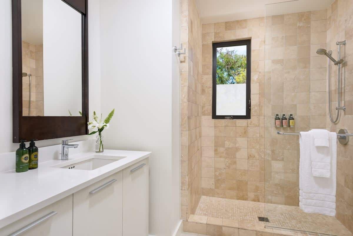 The bathroom has a vanity with one sink and a walk-in shower with beige tiles.