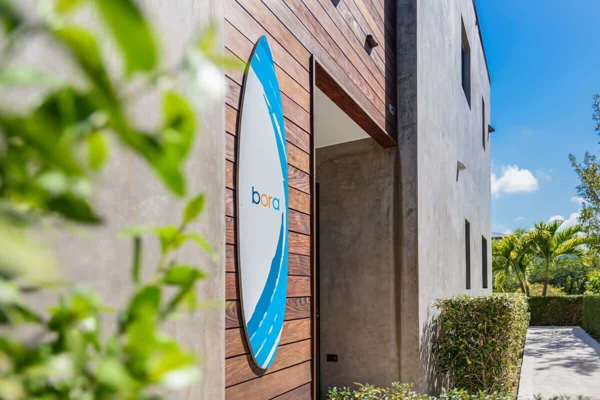A surfboard sign hangs on the wood wall at the entrance of the villa.