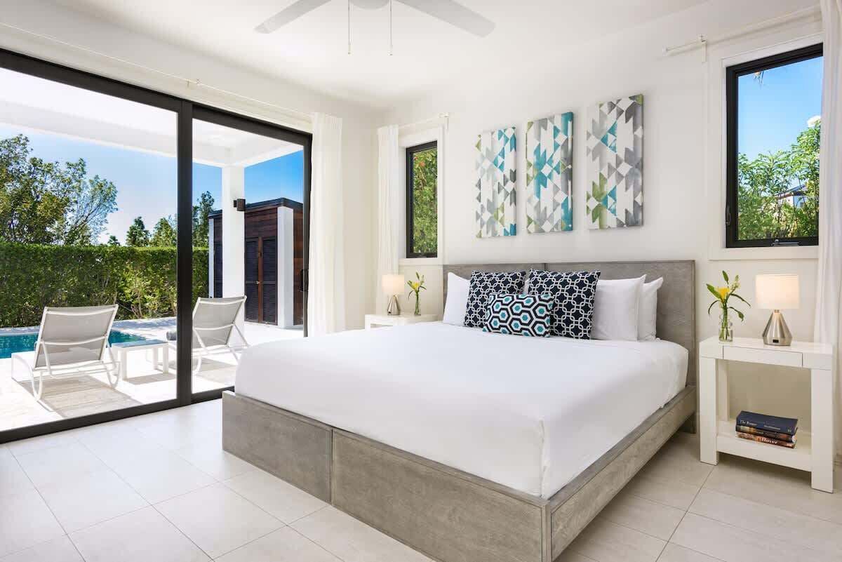 The bedroom has a large bed and a sliding door to the pool terrace.