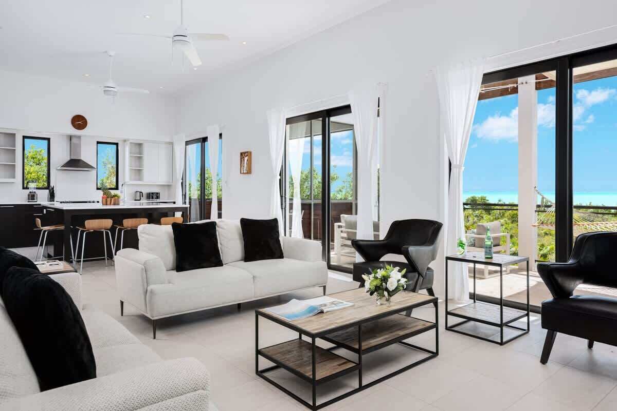 The living room has two sofas, two armchairs, and an open kitchen with a breakfast bar.