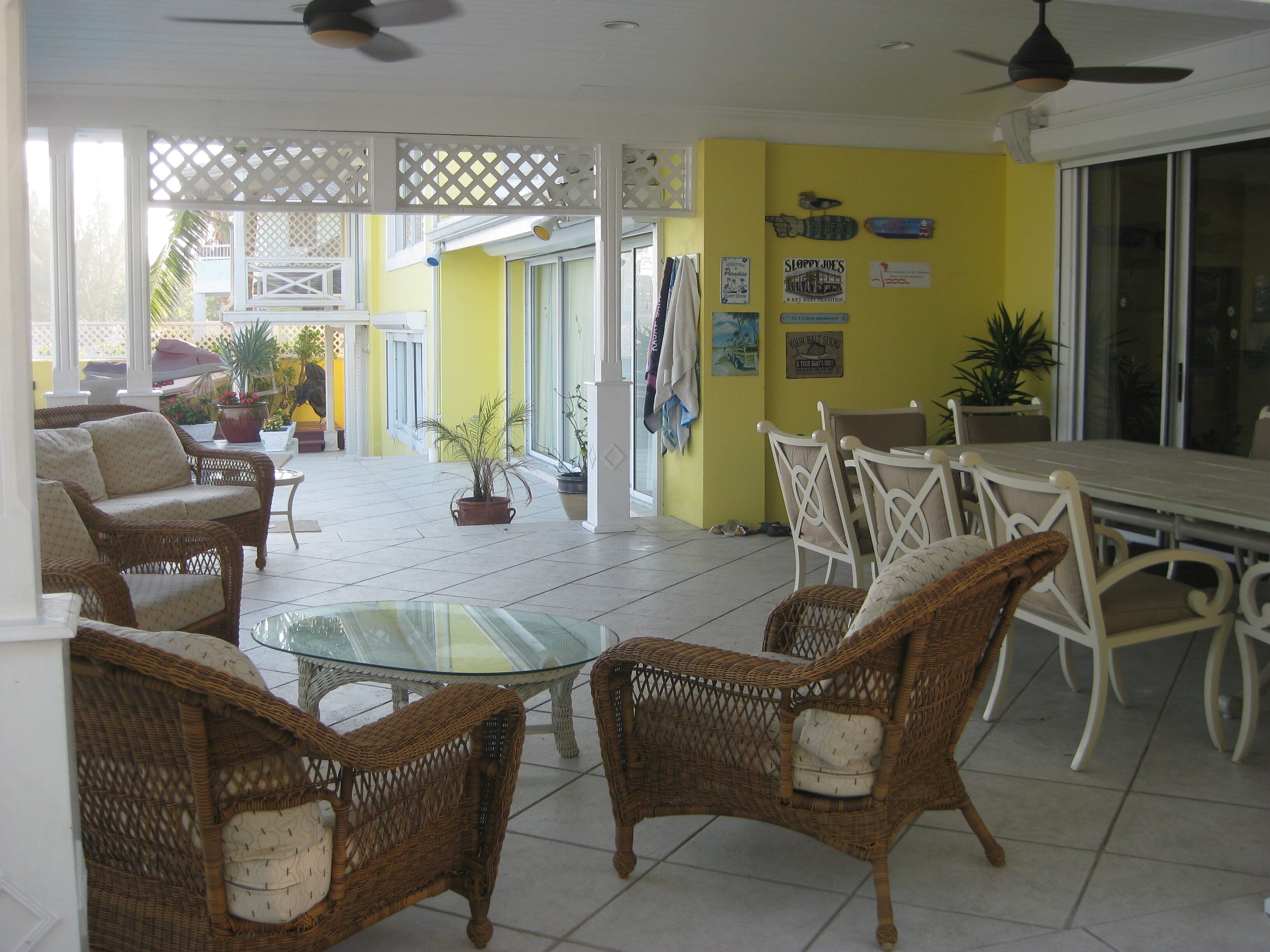 A covered patio with wicker chairs and a long dining table.
