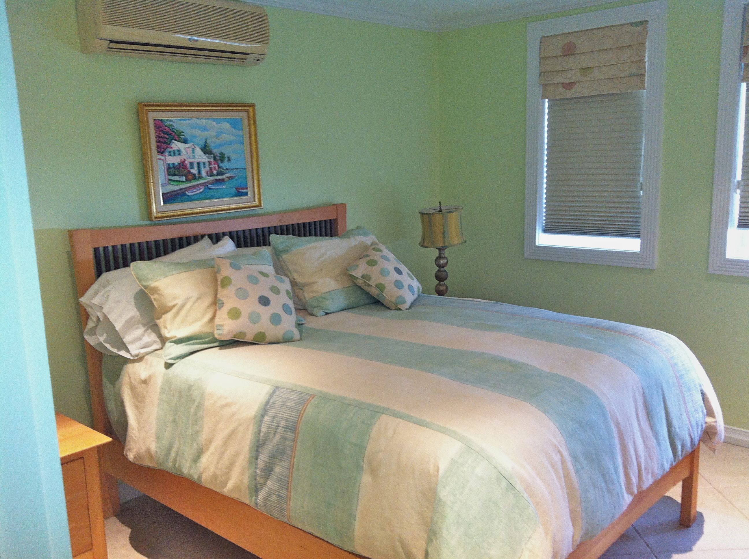 A bedroom with green walls and a bed with striped bedding.