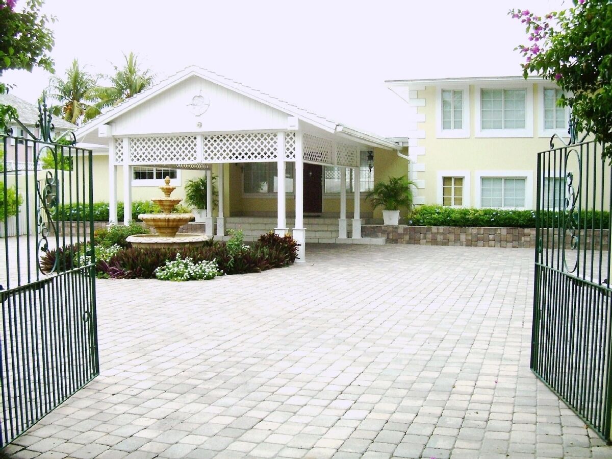 A paved courtyard with a fountain in front of the covered entrance.