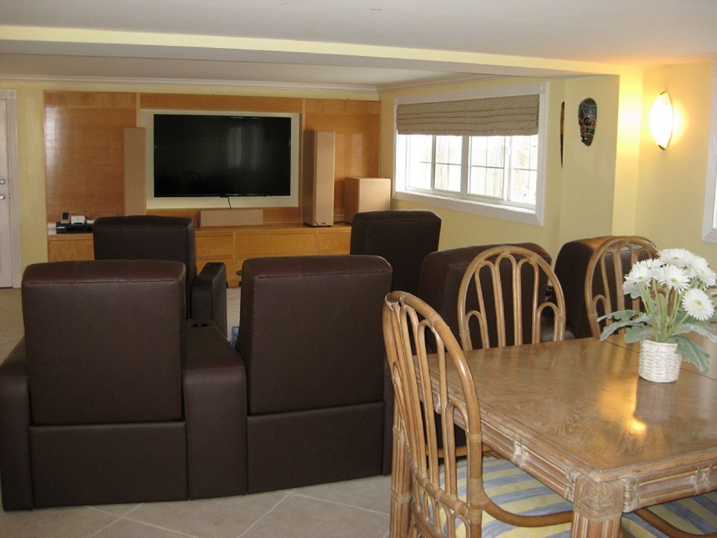 A media room with leather recliners, a large television, and a dining table.