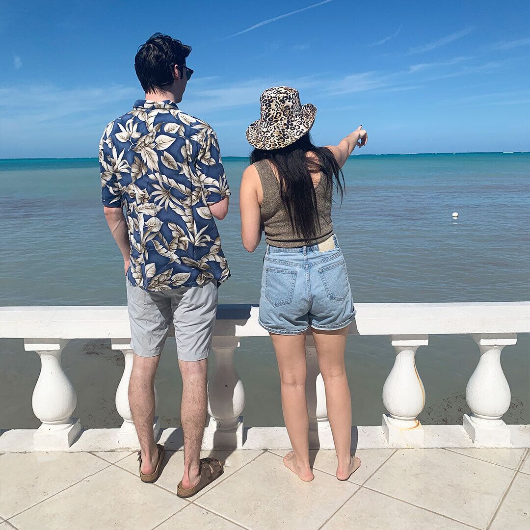 Two people stand at the balustrade and look at the sea.