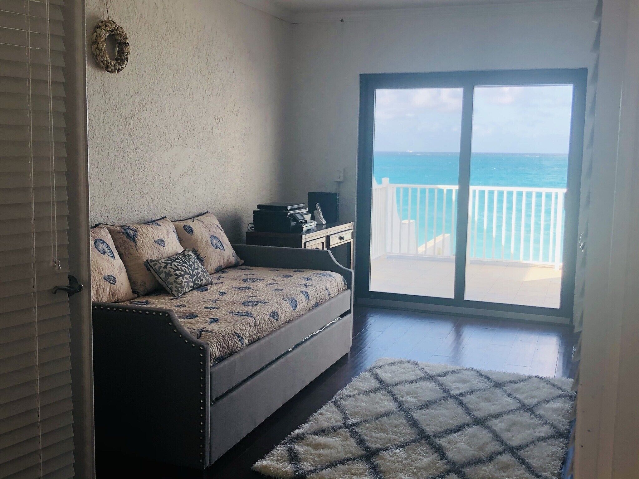 A room with a daybed and a sliding door to the balcony.