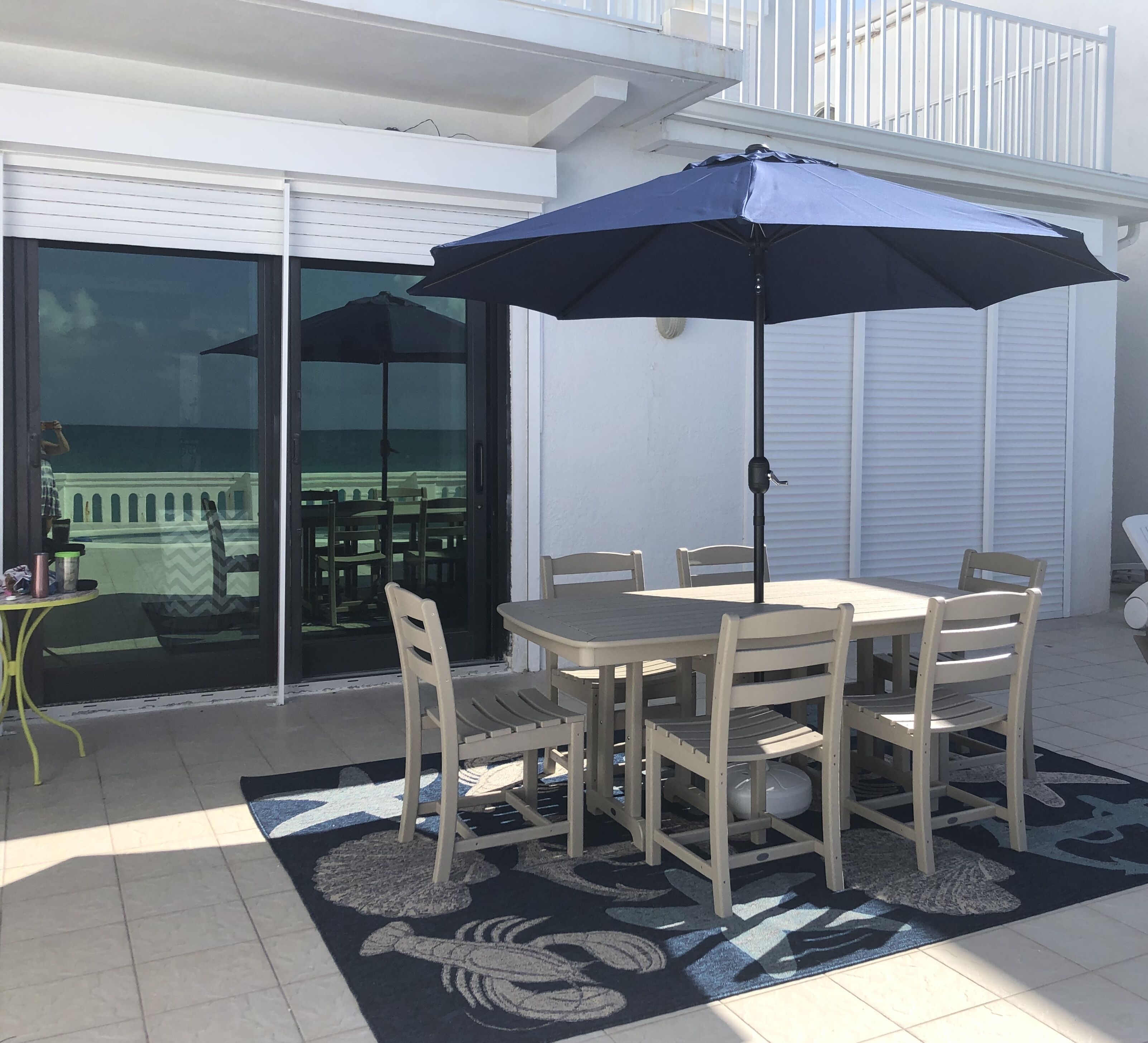 The patio dining table with six chairs and a navy umbrella.