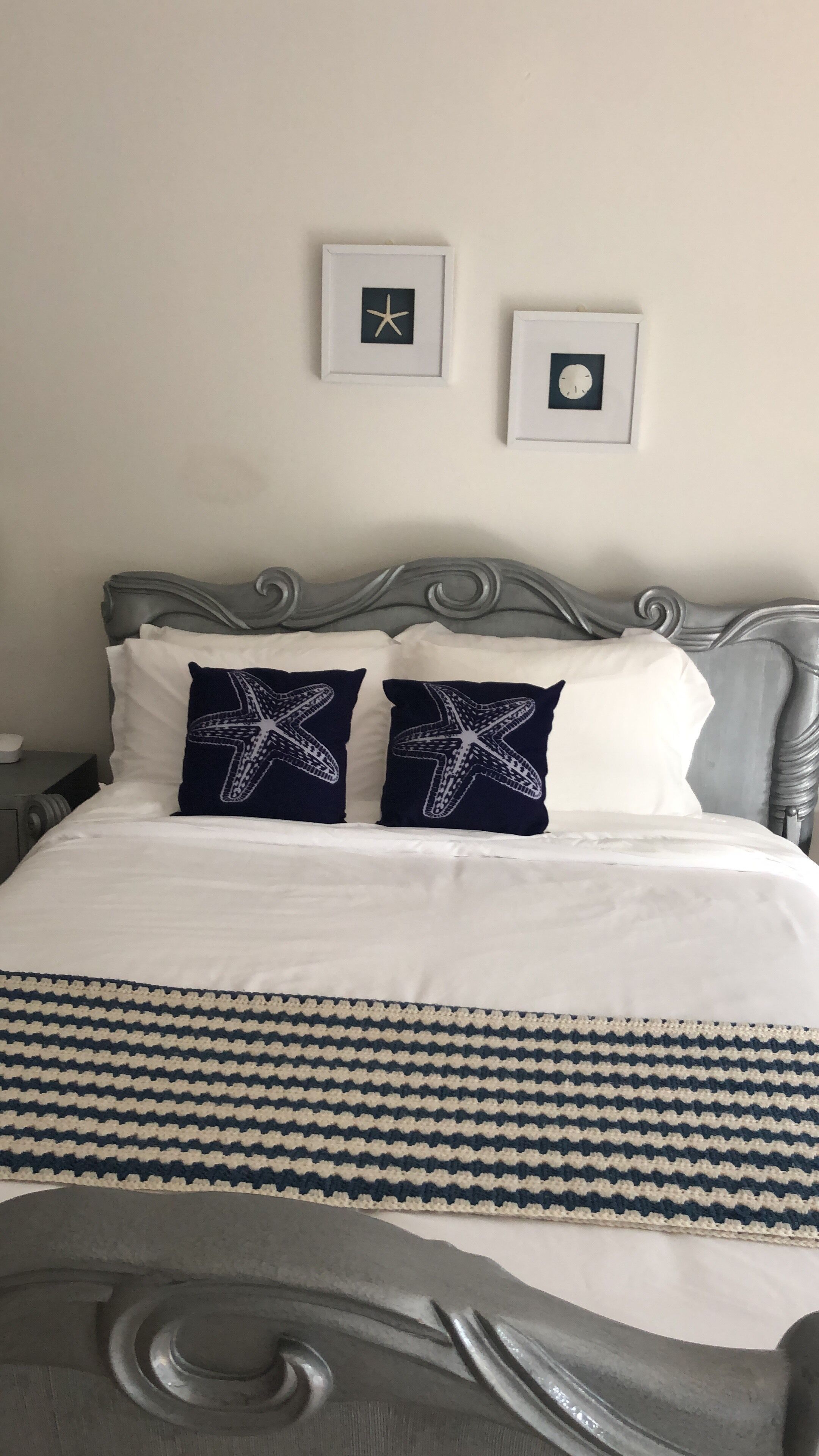 A bed with a silver headboard and two starfish pillows.